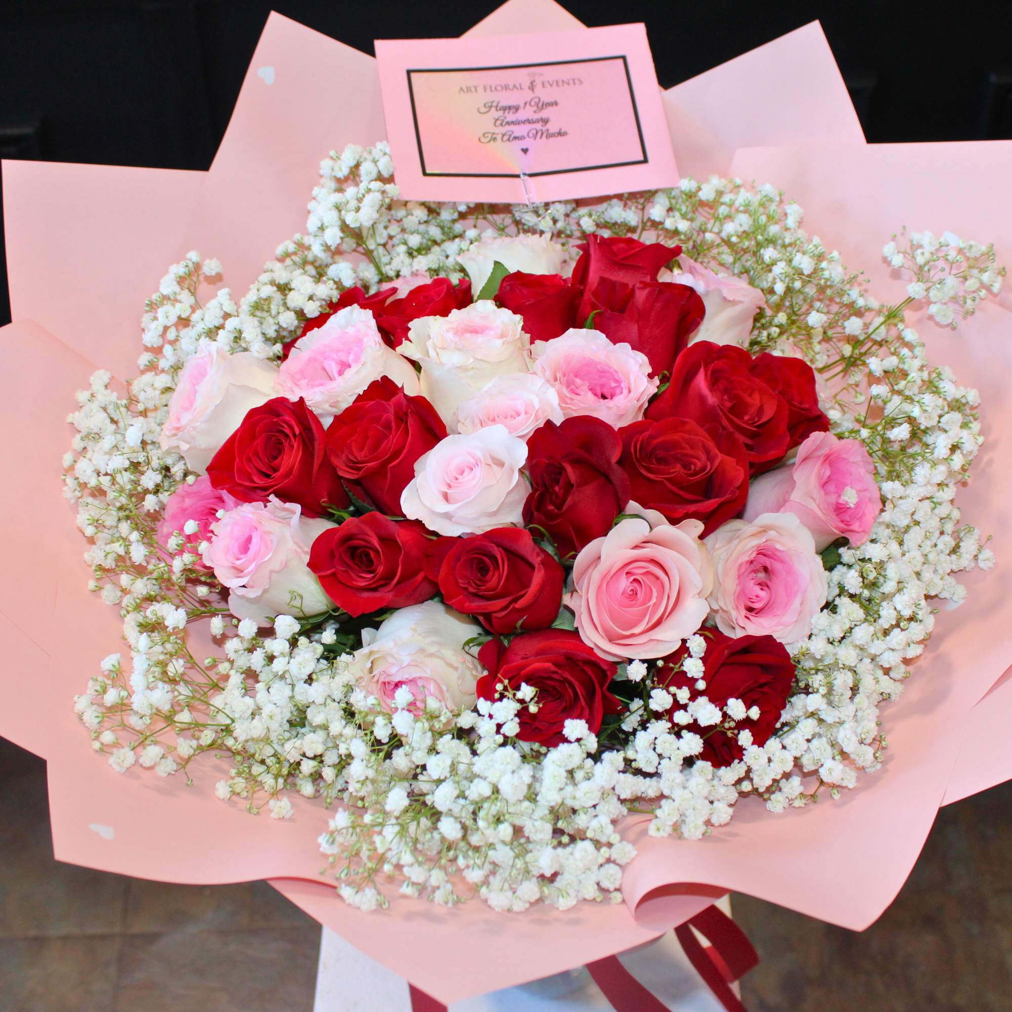 Bouquet of red and pink roses with white baby's breath in pink wrapping