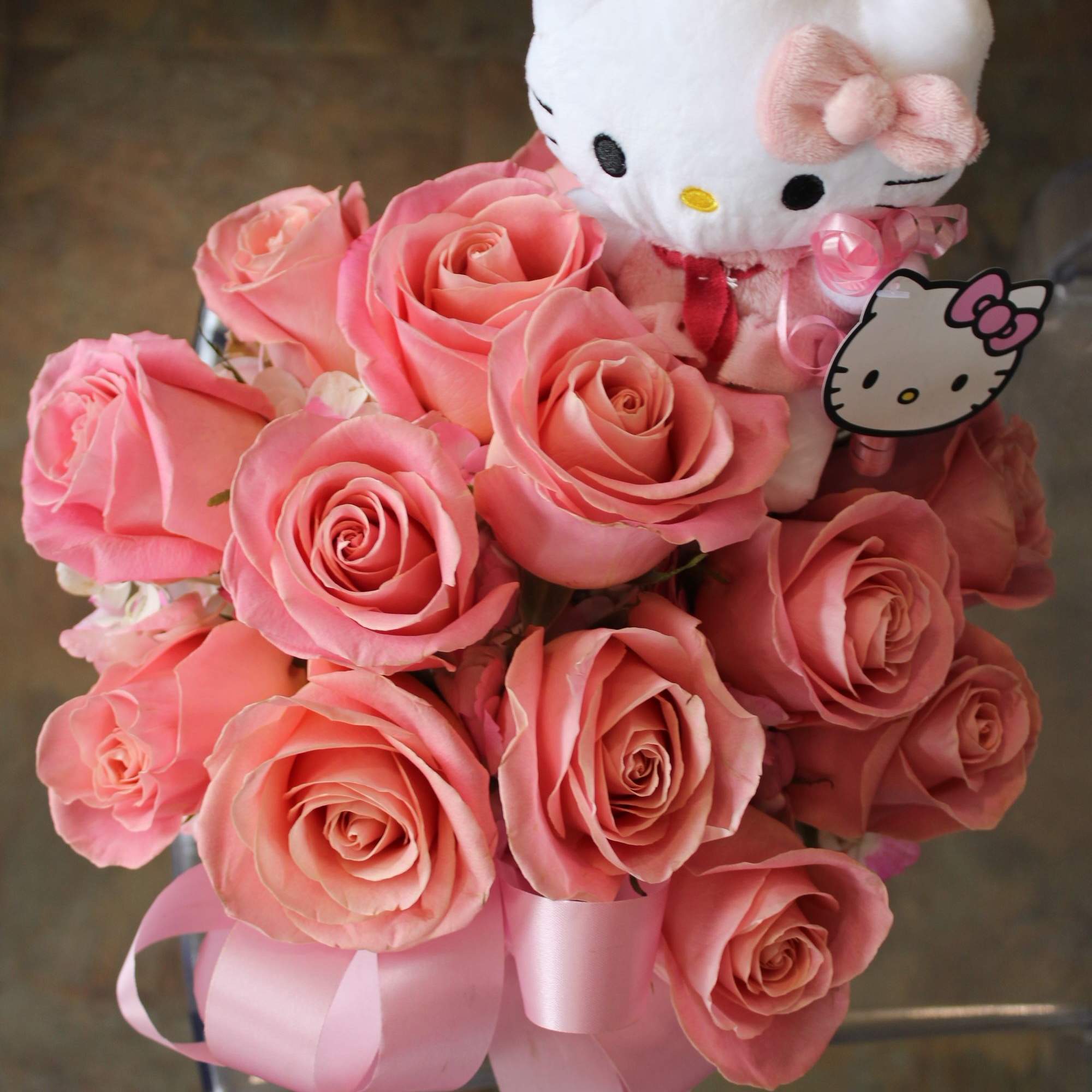 Pink roses arranged with a Hello Kitty plush and pink ribbon
