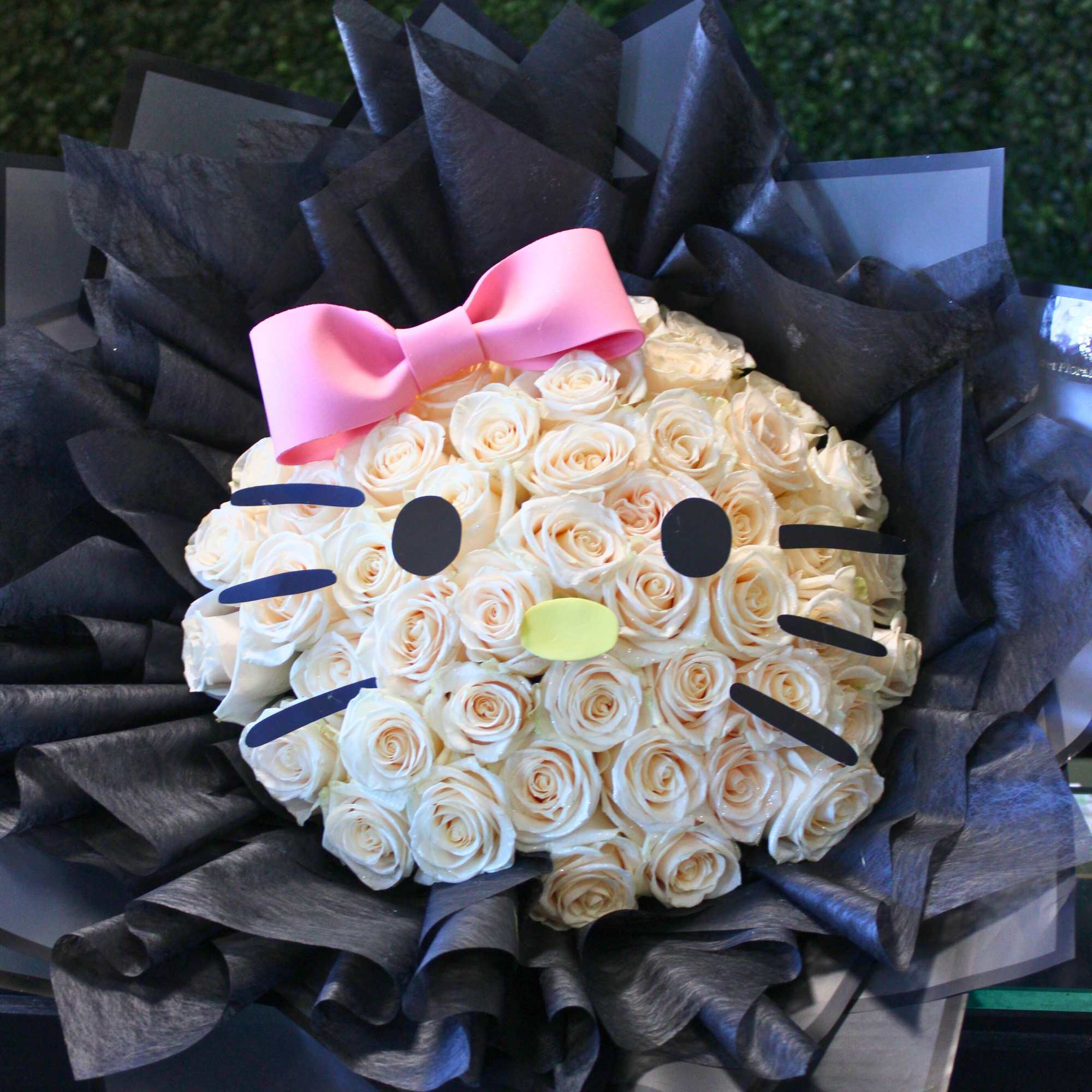 Bouquet of cream roses styled like a Hello Kitty face with a pink bow