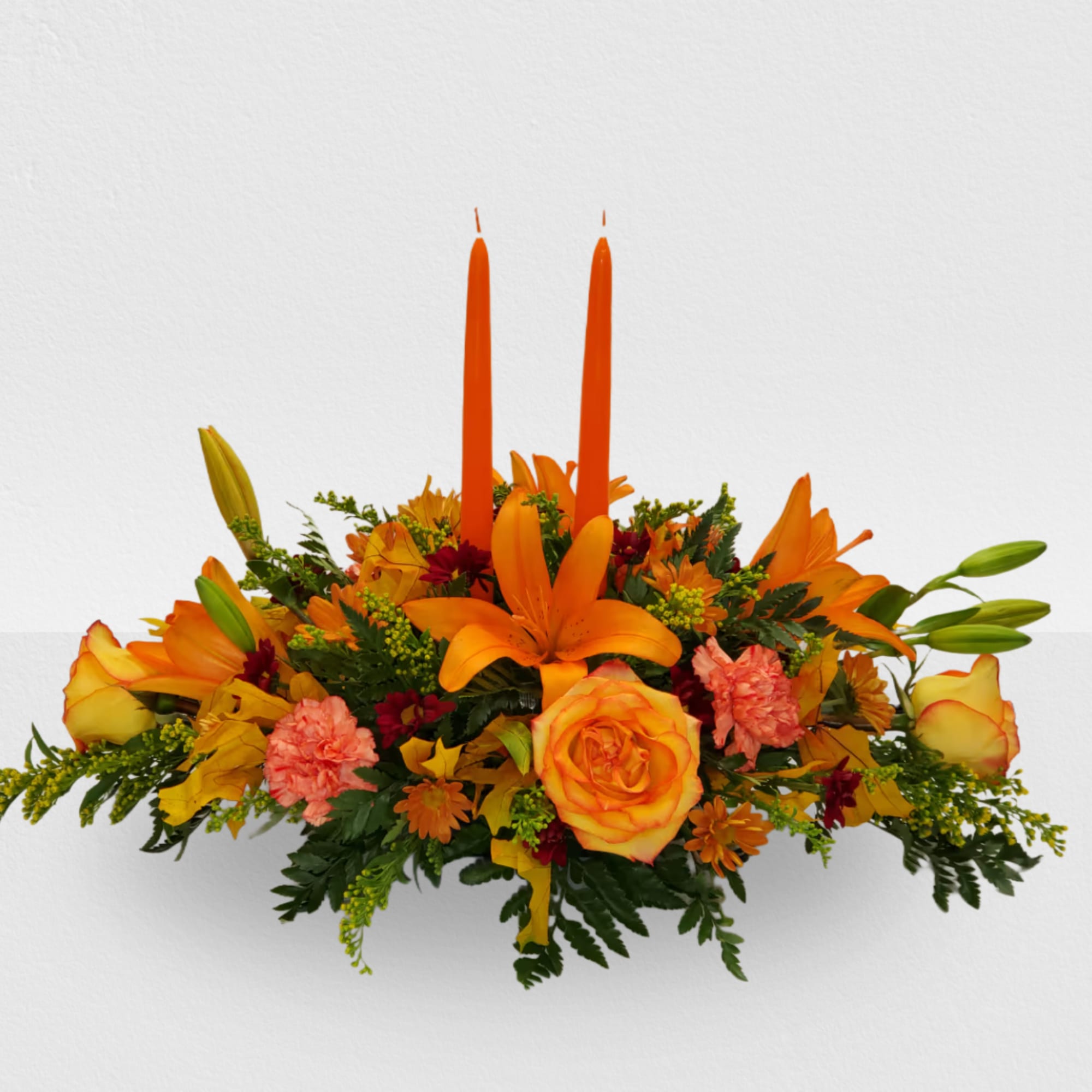 Orange floral centerpiece with two tall candles