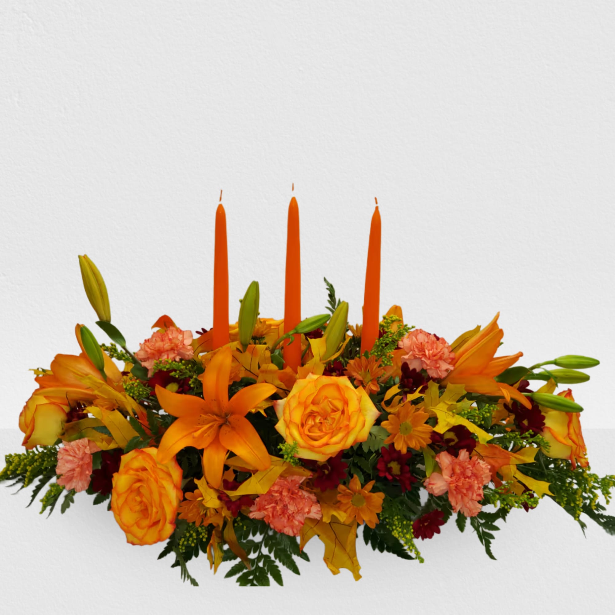 Orange floral centerpiece with three tall candles