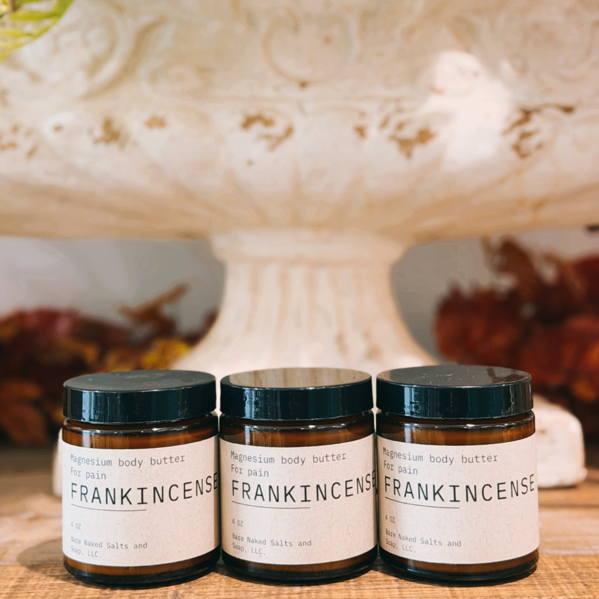 Three jars of frankincense magnesium body butter on a wooden surface