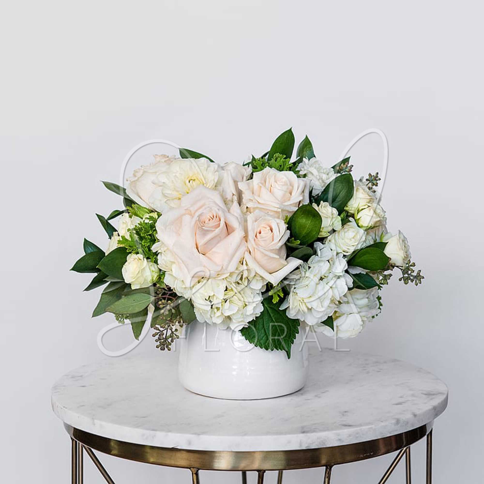 White and blush roses arranged in a white vase