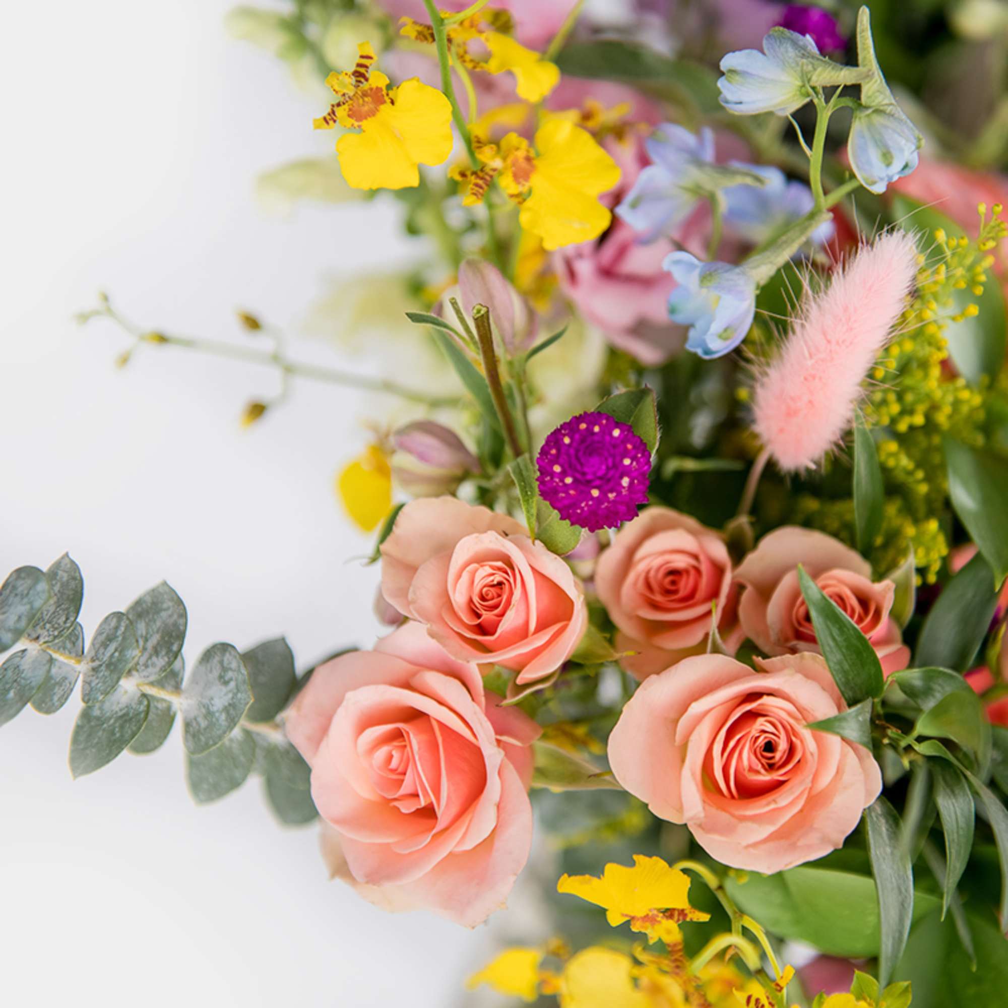 Colorful bouquet with peach roses, yellow orchids, purple blooms, and mixed pastel flowers