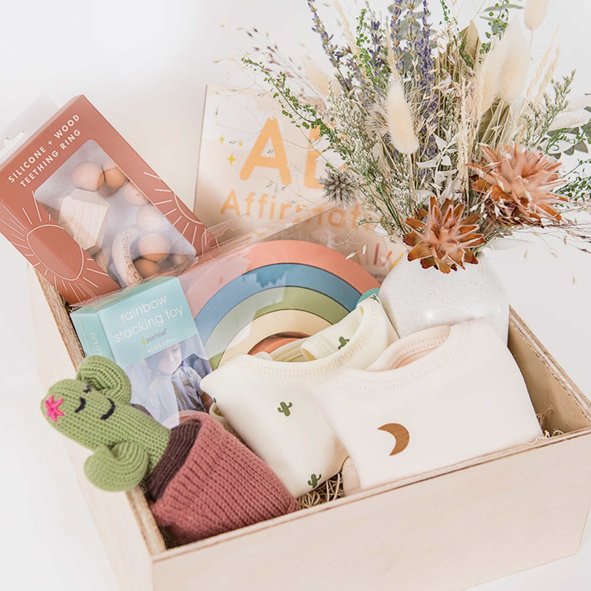 Gift basket with baby clothes, toys, and a dried floral arrangement