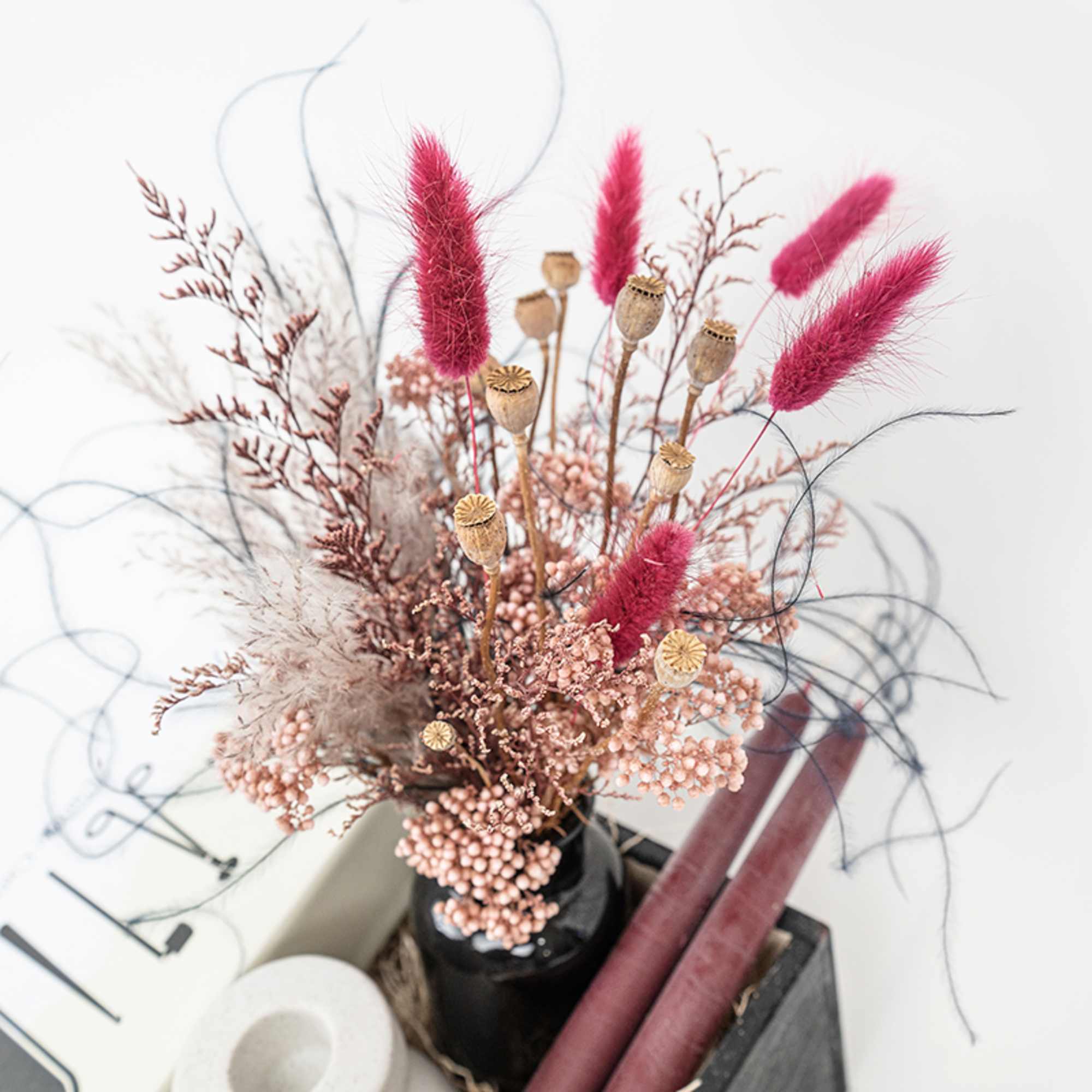 Dried floral arrangement with pink bunny tails in a black vase