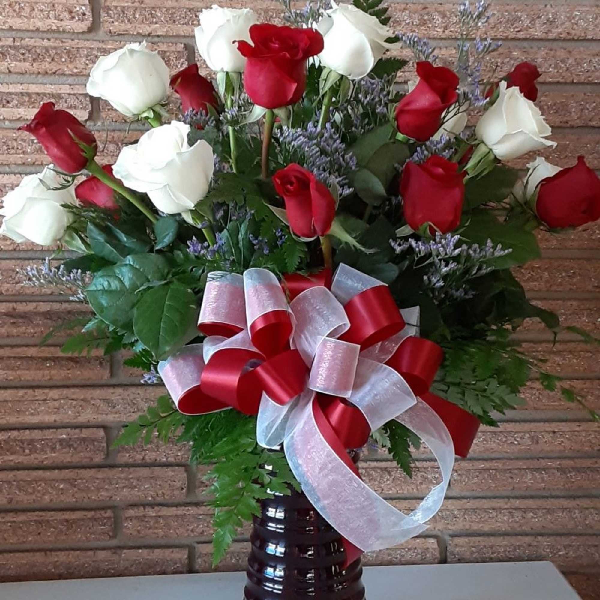 Bouquet of red and white roses with a red-and-white ribbon in a vase
