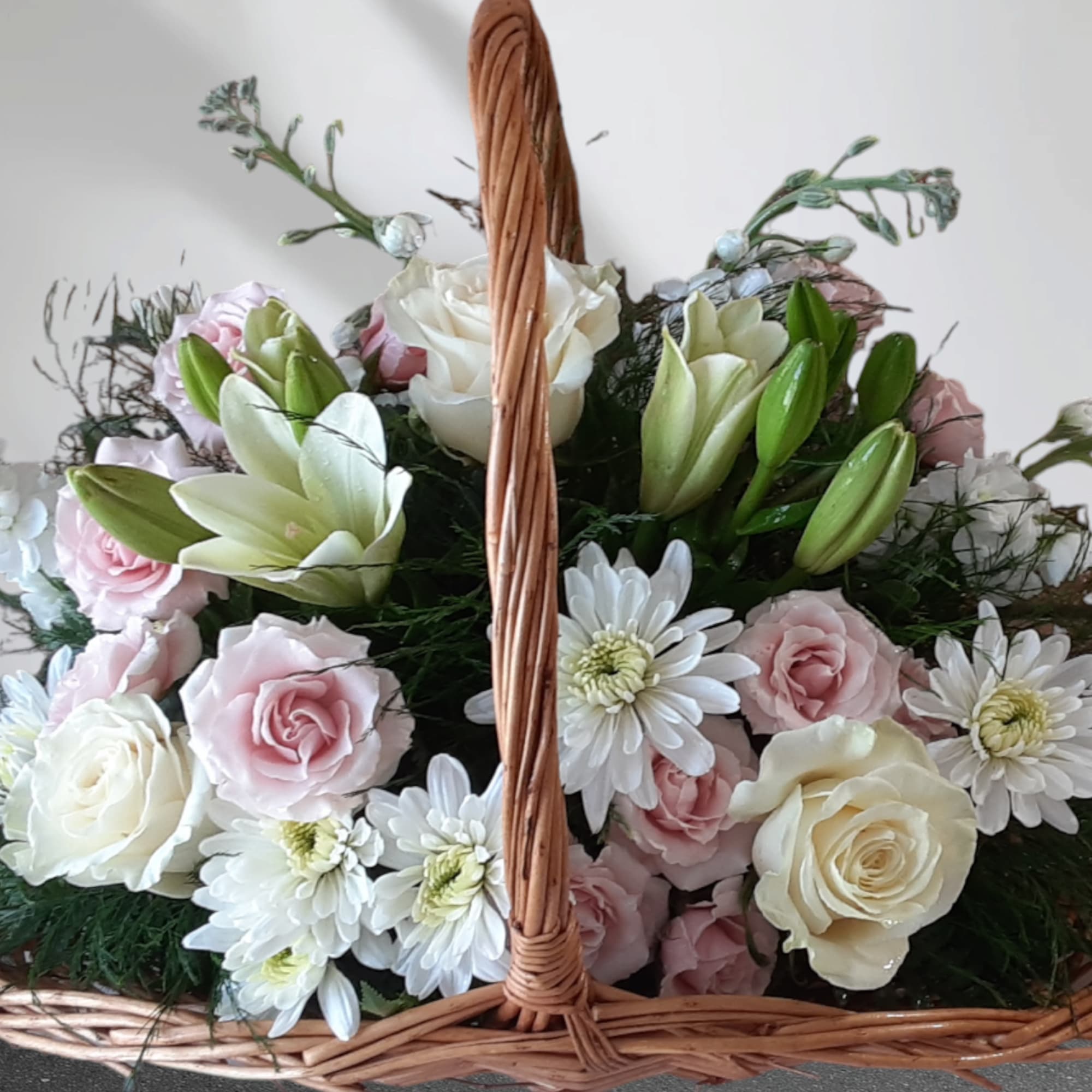 Basket of pink and white roses with white daisies and lilies