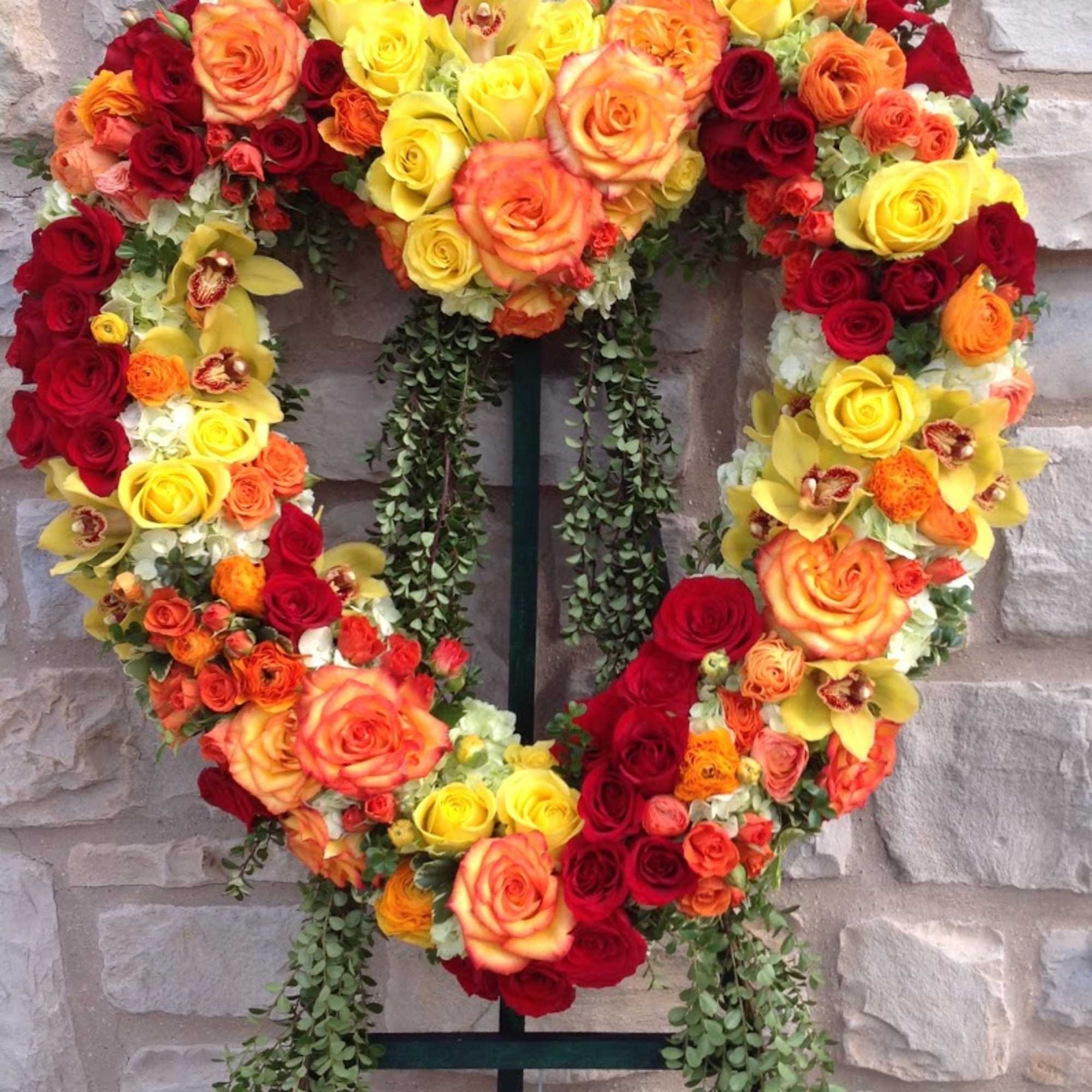 Heart-shaped floral wreath of red, orange, and yellow roses