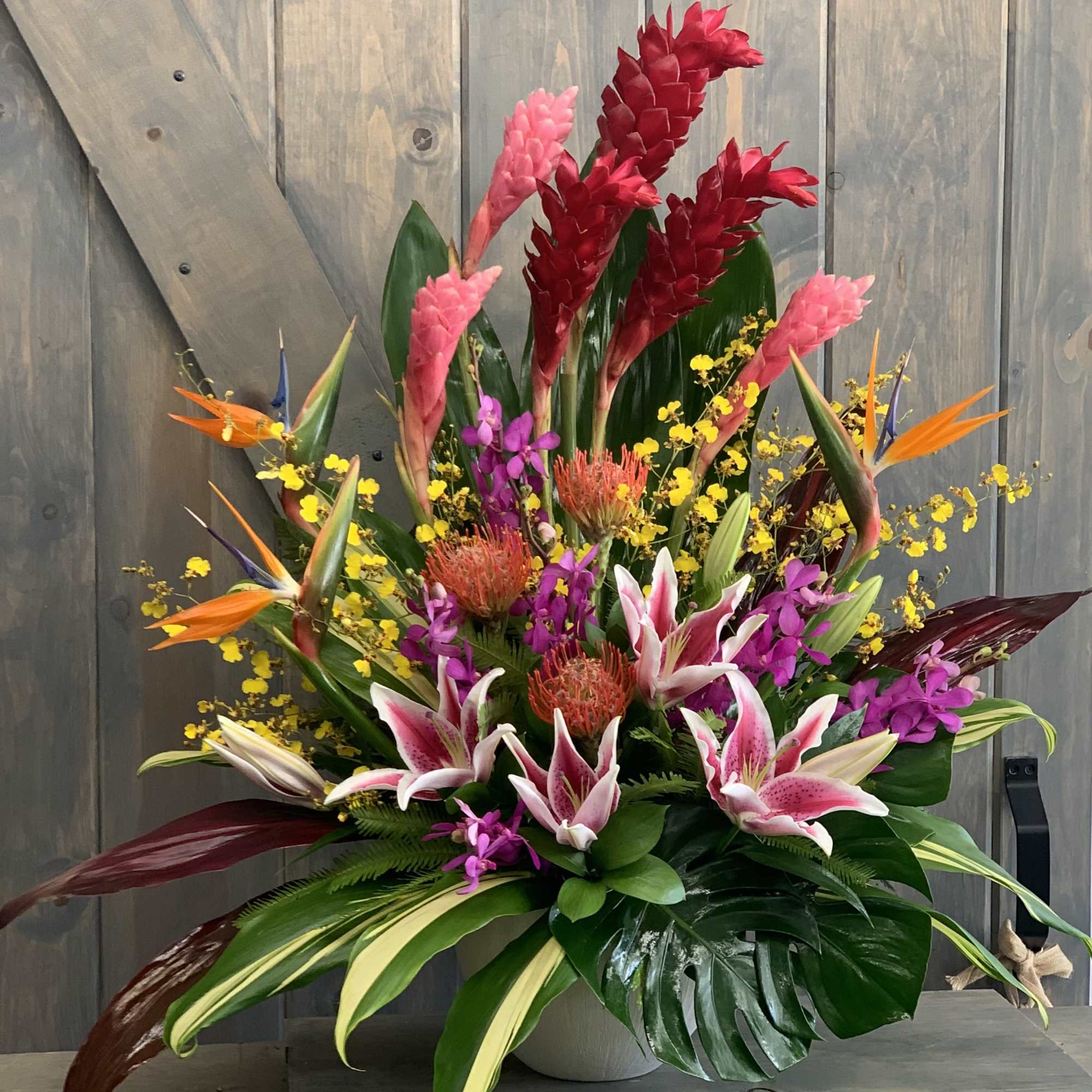 Tropical bouquet with pink lilies and red ginger in a vase