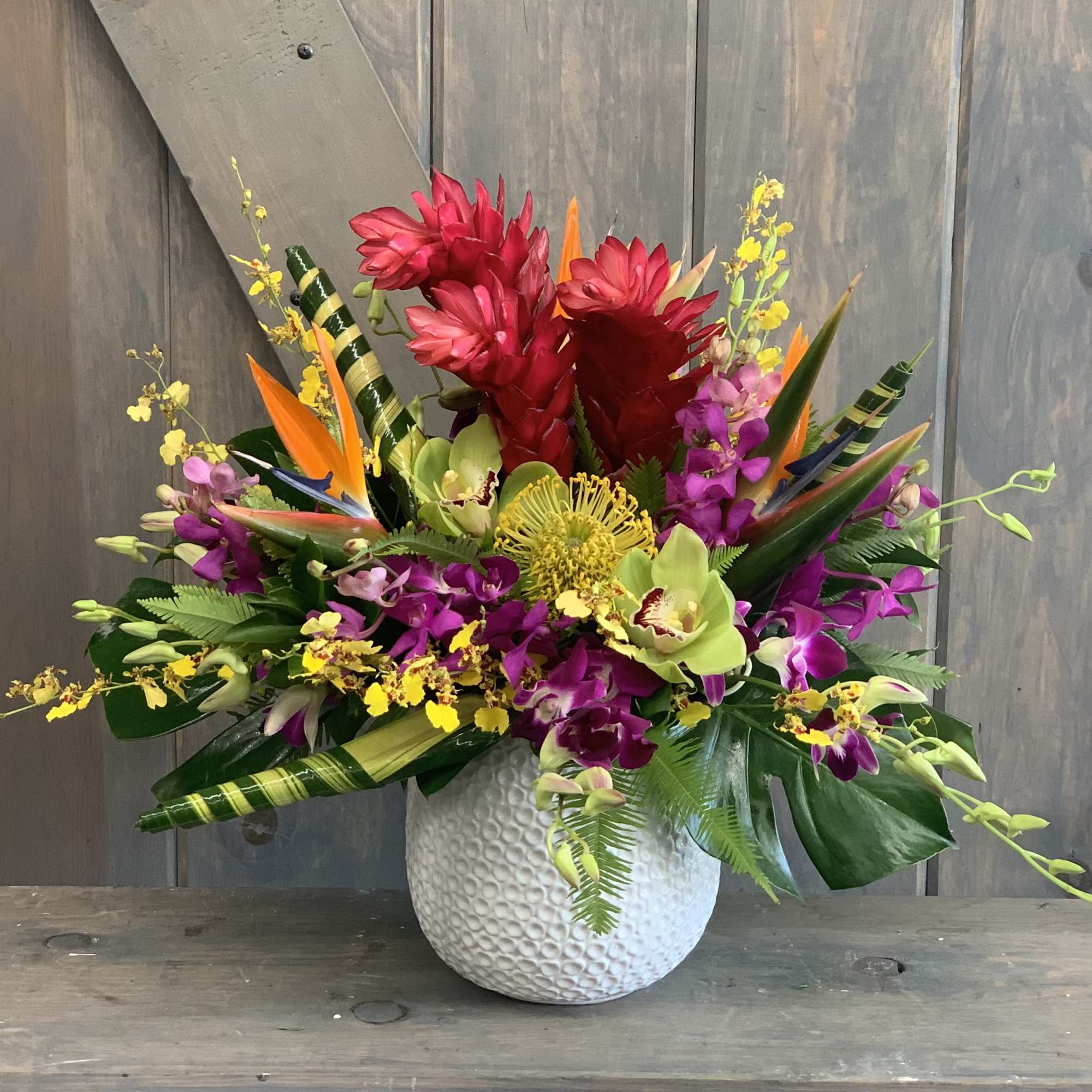 Tropical flower arrangement in a white textured vase