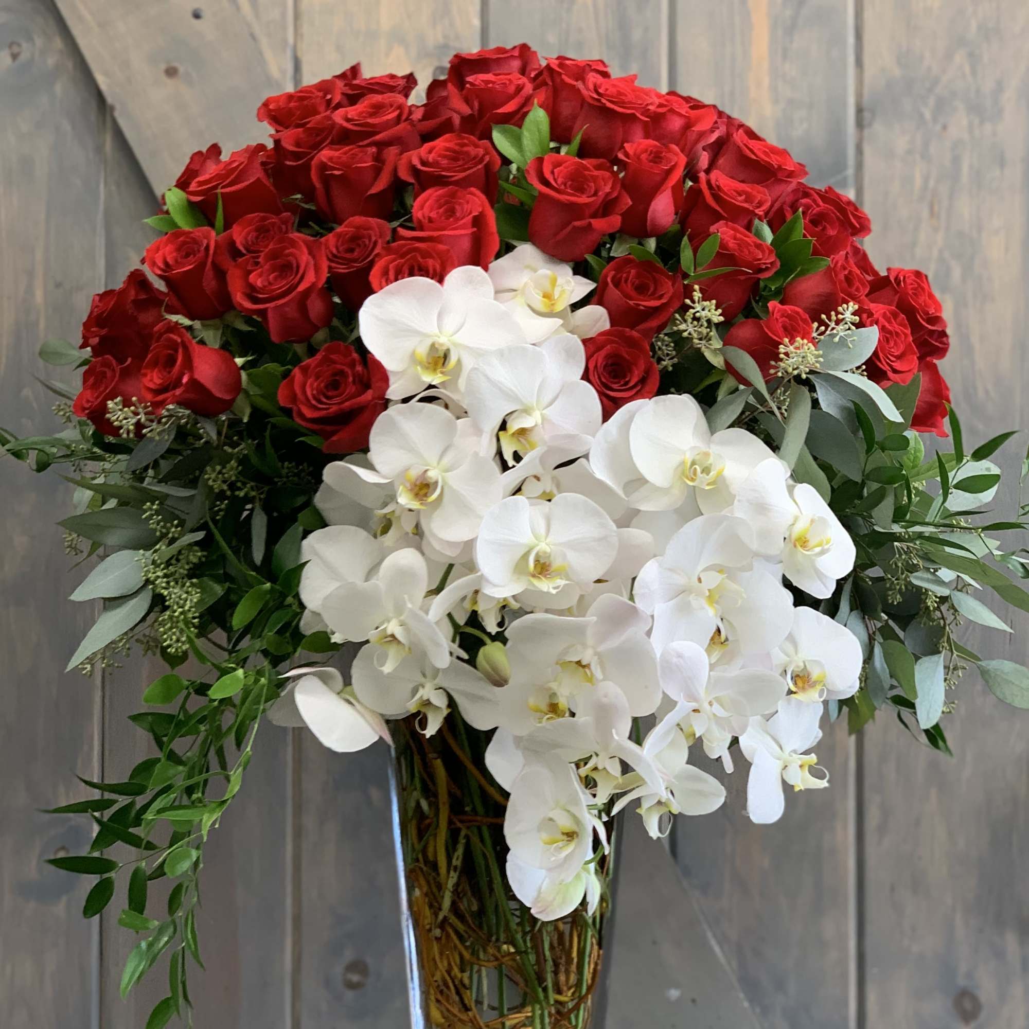Red roses and white orchids arranged in a clear glass vase