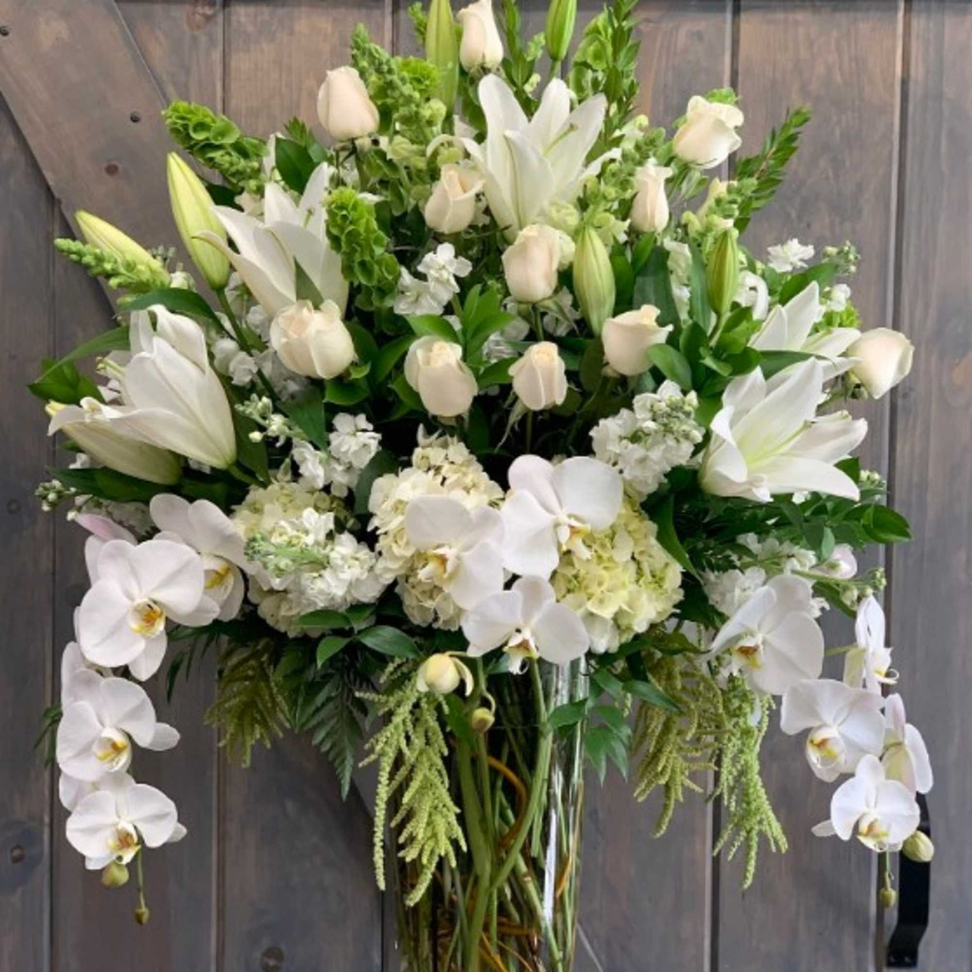 White lilies and orchids in a clear glass vase