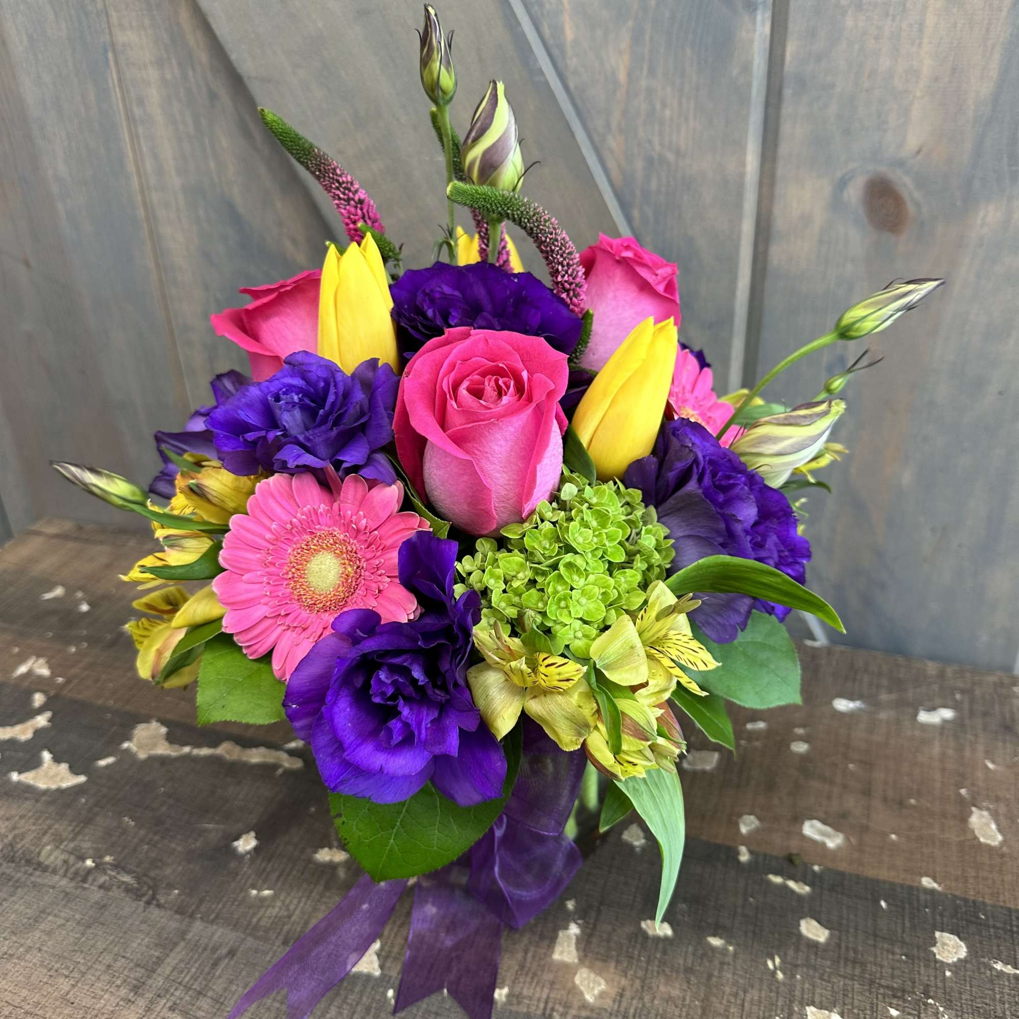 Bright mixed bouquet with pink roses, purple blooms, and yellow tulips