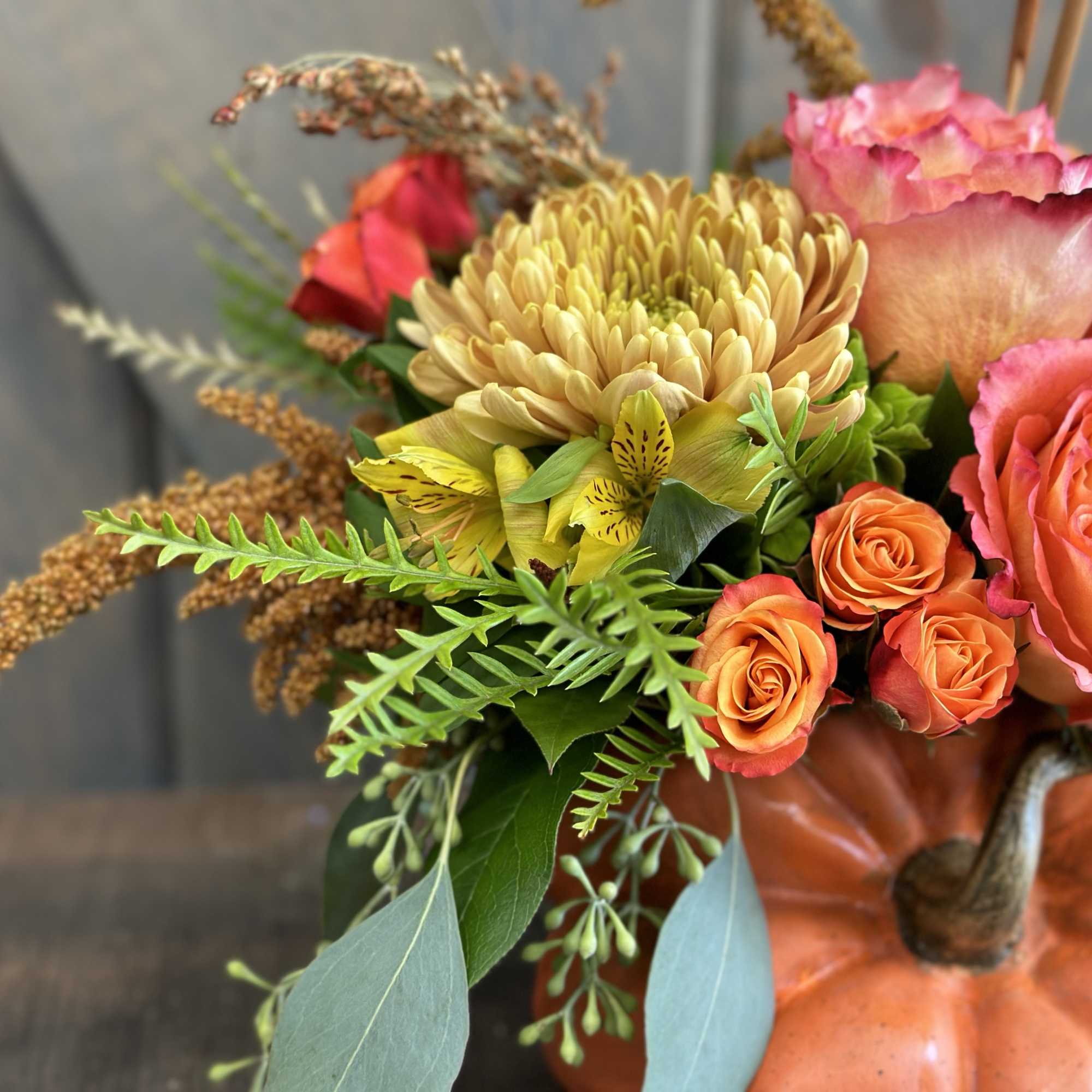 Bouquet of orange and pink flowers arranged in a pumpkin container