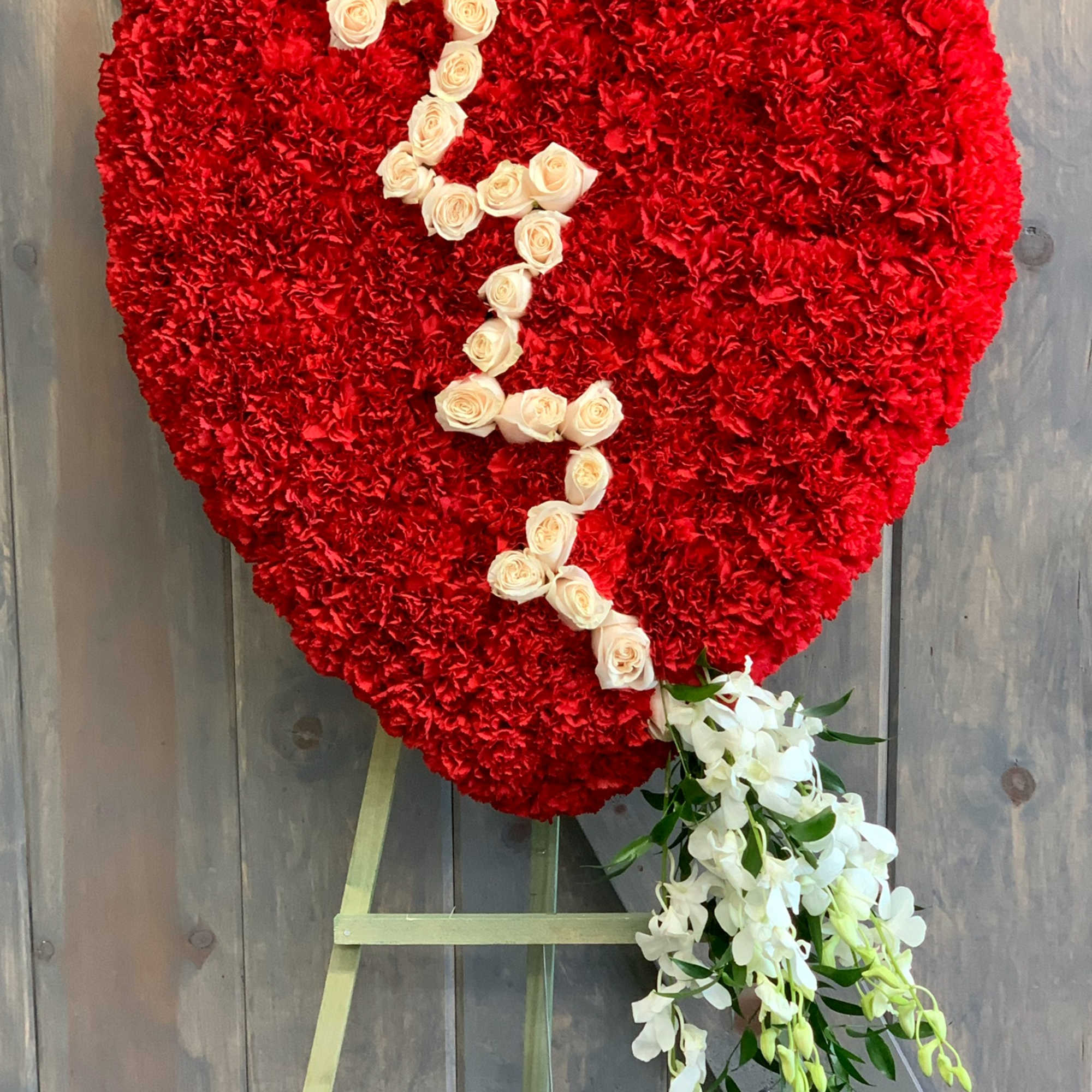 Heart-shaped red floral tribute with white roses and hanging white orchids