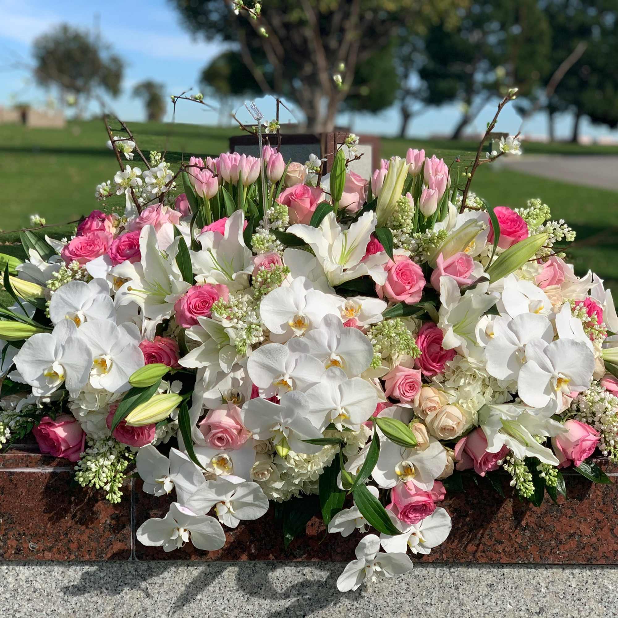 Pink and white floral arrangement with orchids, roses, and lilies
