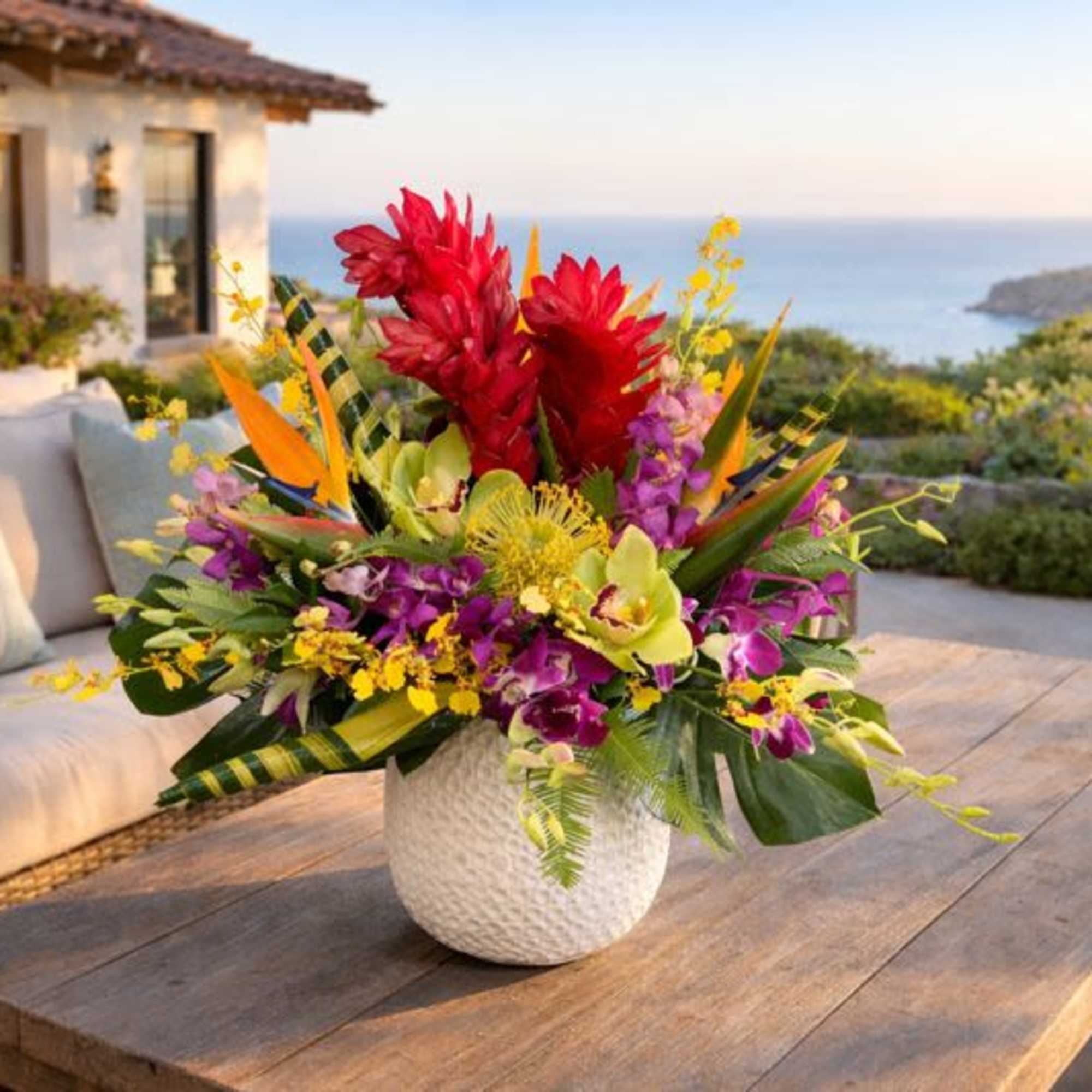 Tropical flower arrangement in a white textured vase on a wooden table