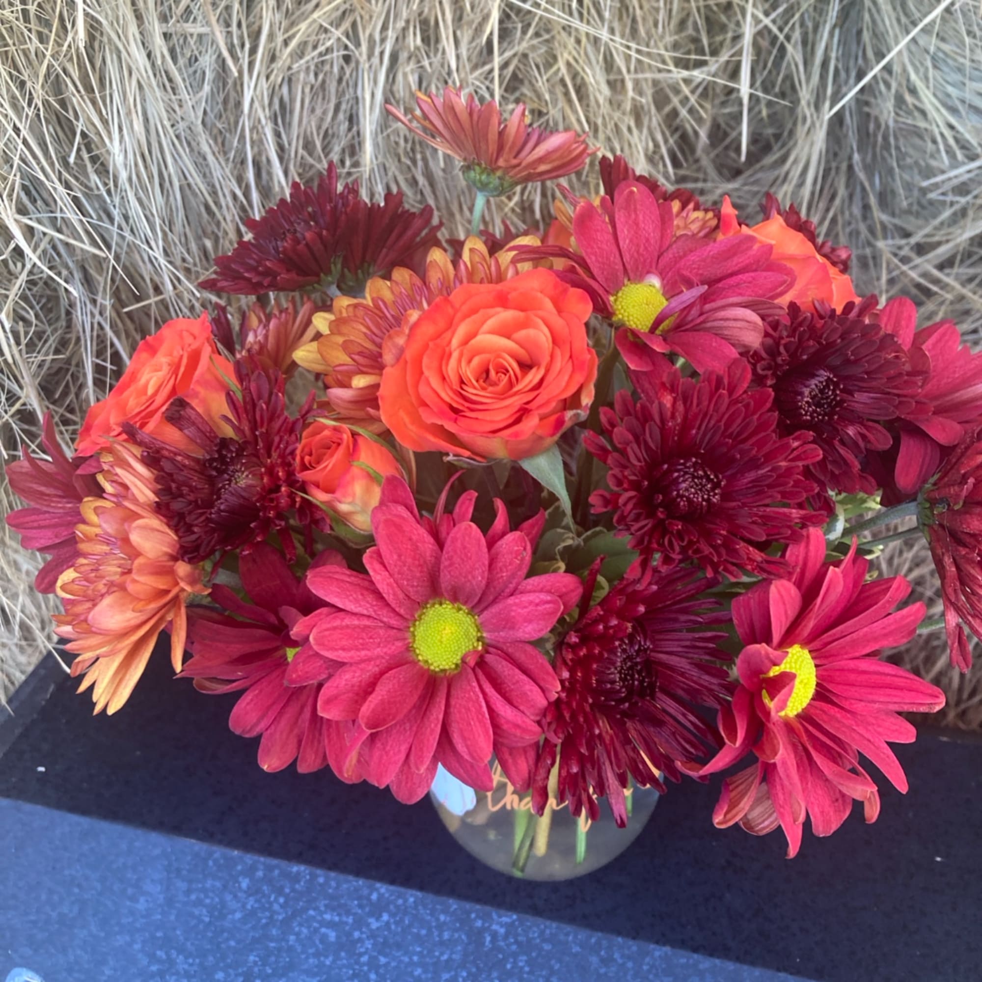 Bouquet of orange roses and pink daisies in a glass vase