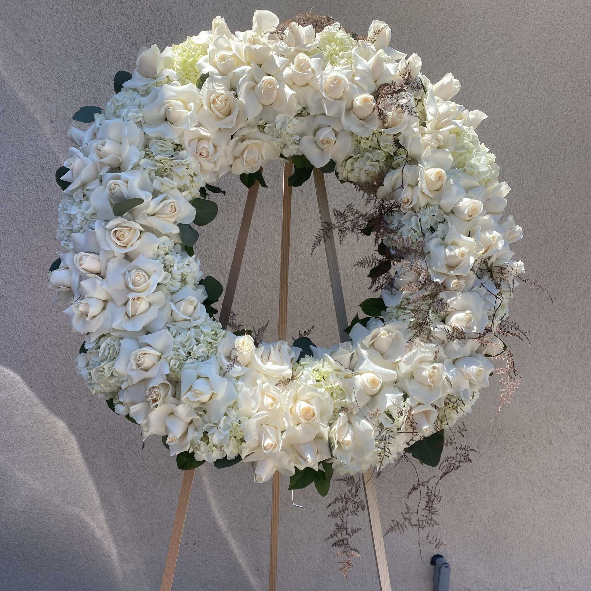 Large white floral wreath on a wooden easel