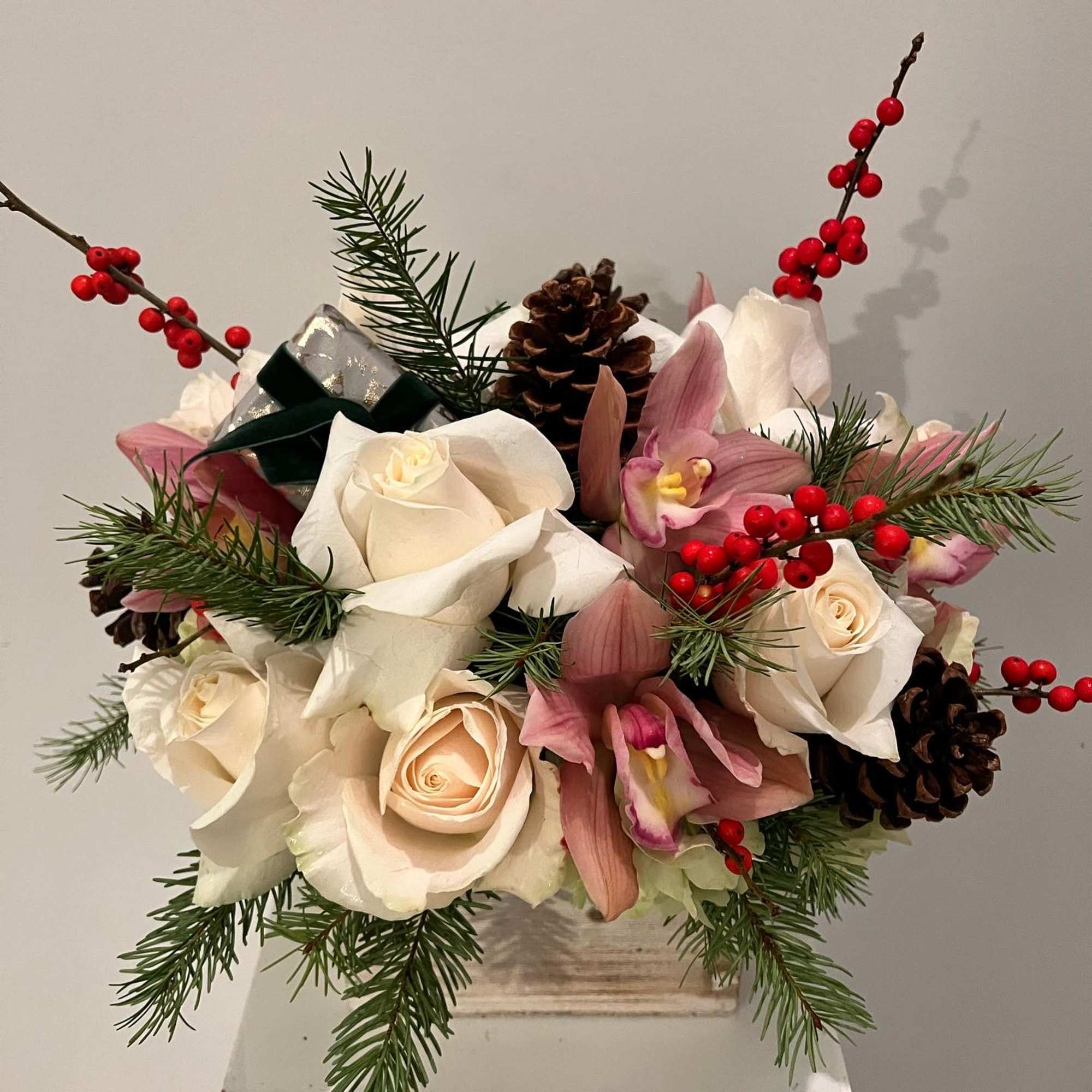 Bouquet of white roses and pink orchids with pinecones and red berries