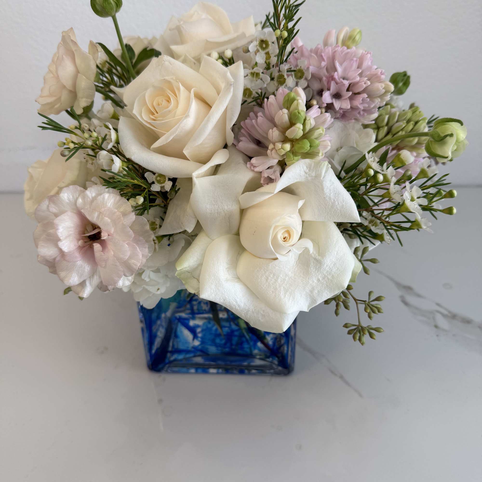 Bouquet of white roses and pale pink flowers in a blue glass vase