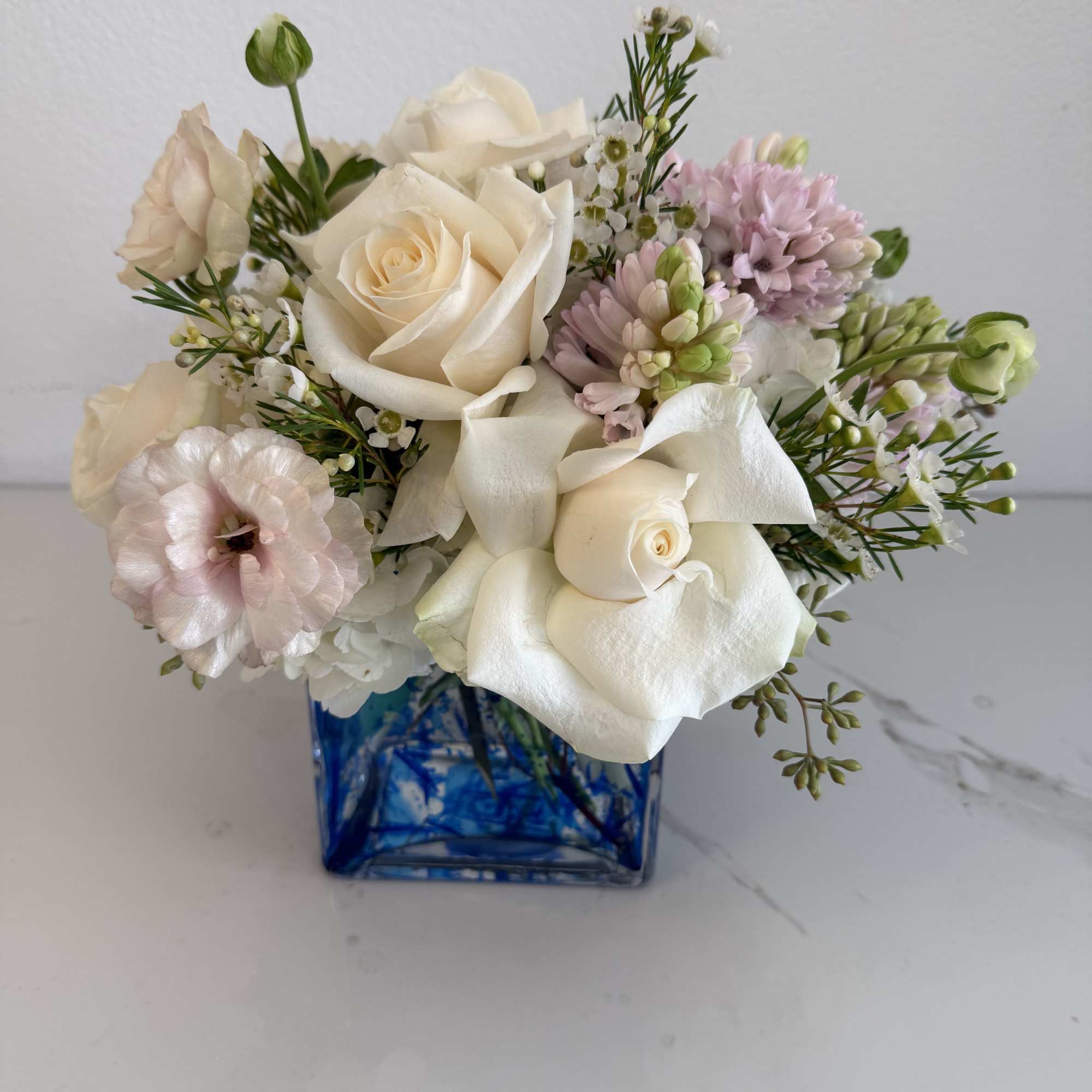 Cream roses and pale pink flowers in a blue glass vase