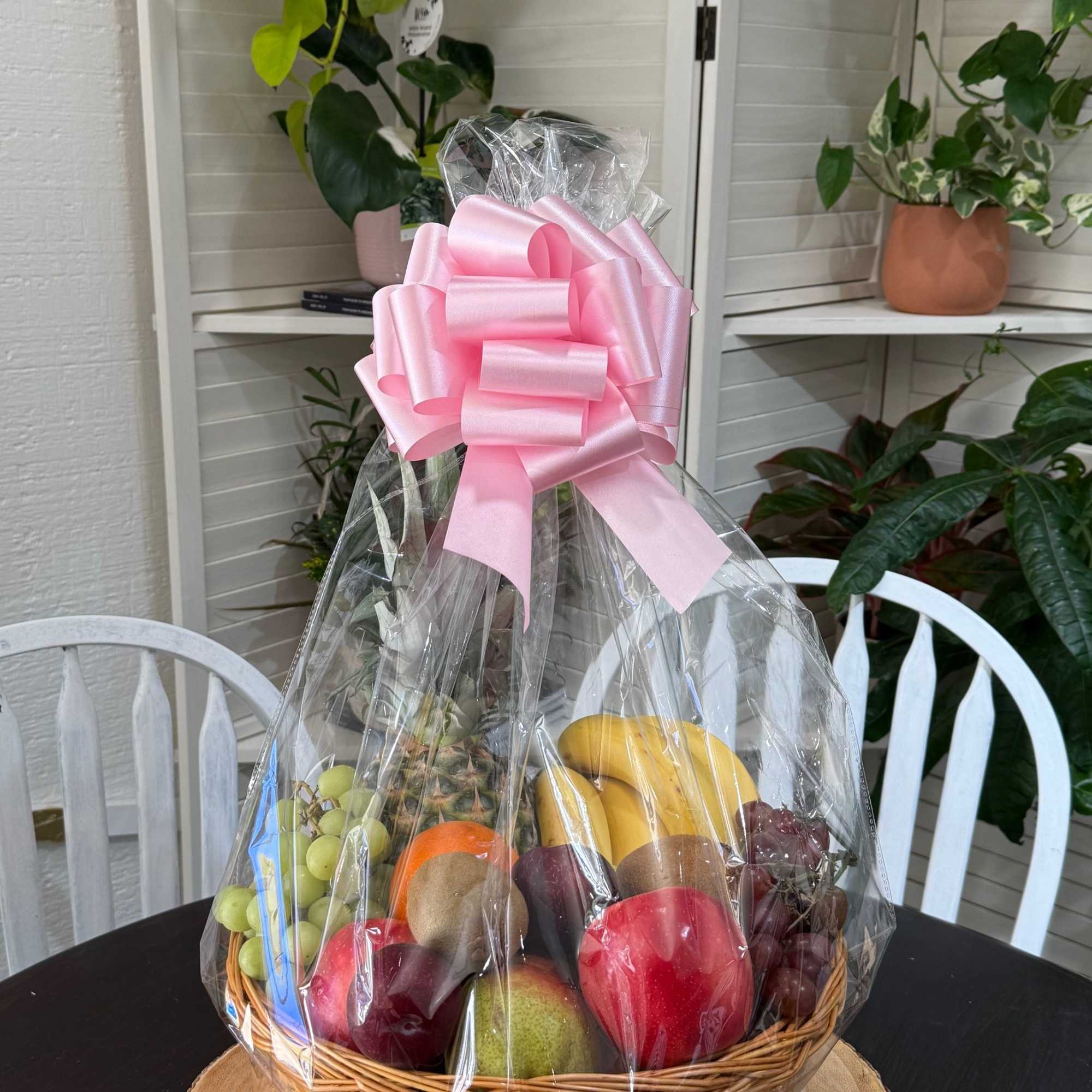 Fruit basket wrapped in clear cellophane with a pink bow