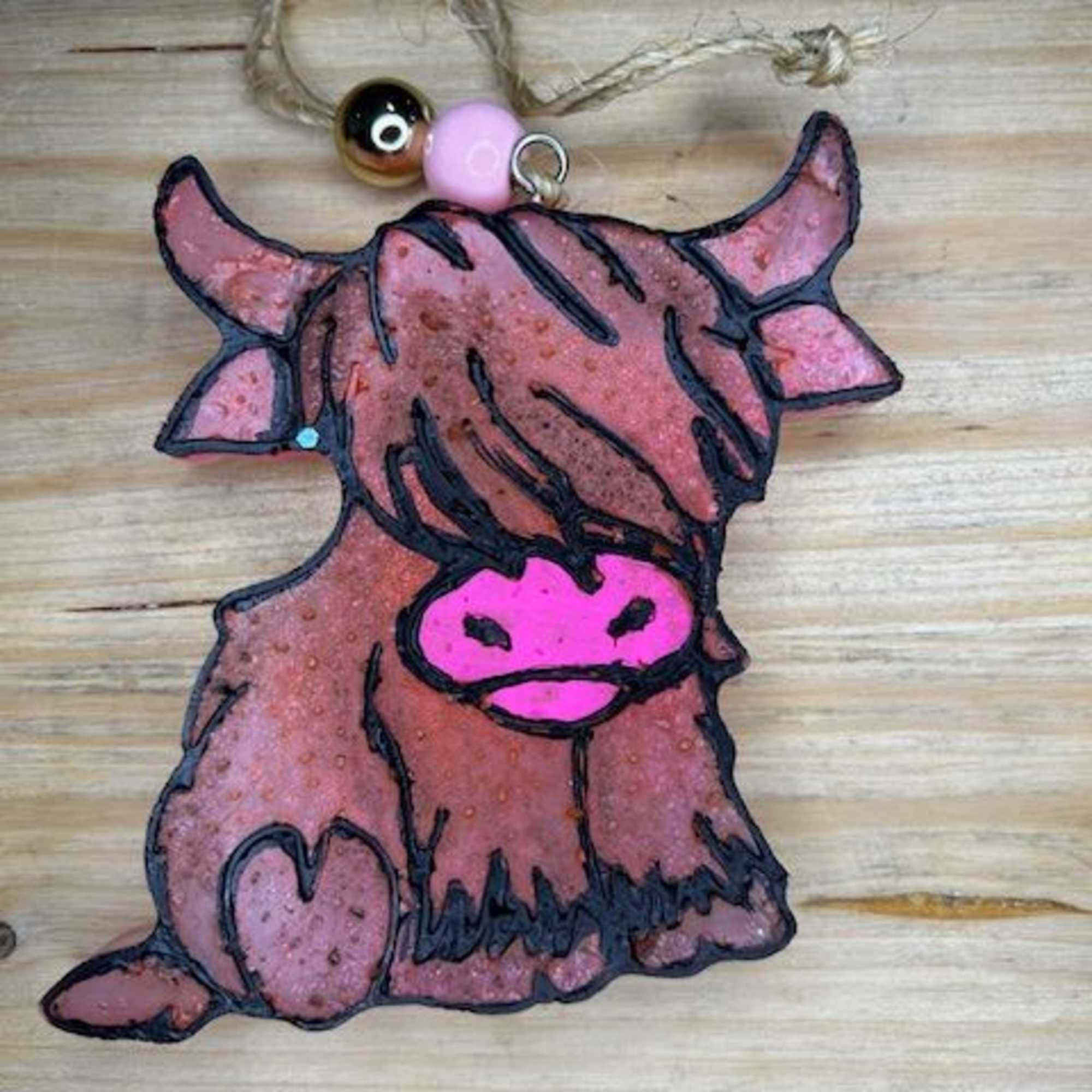 Handmade cow-shaped ornament with a twine hanger and beads