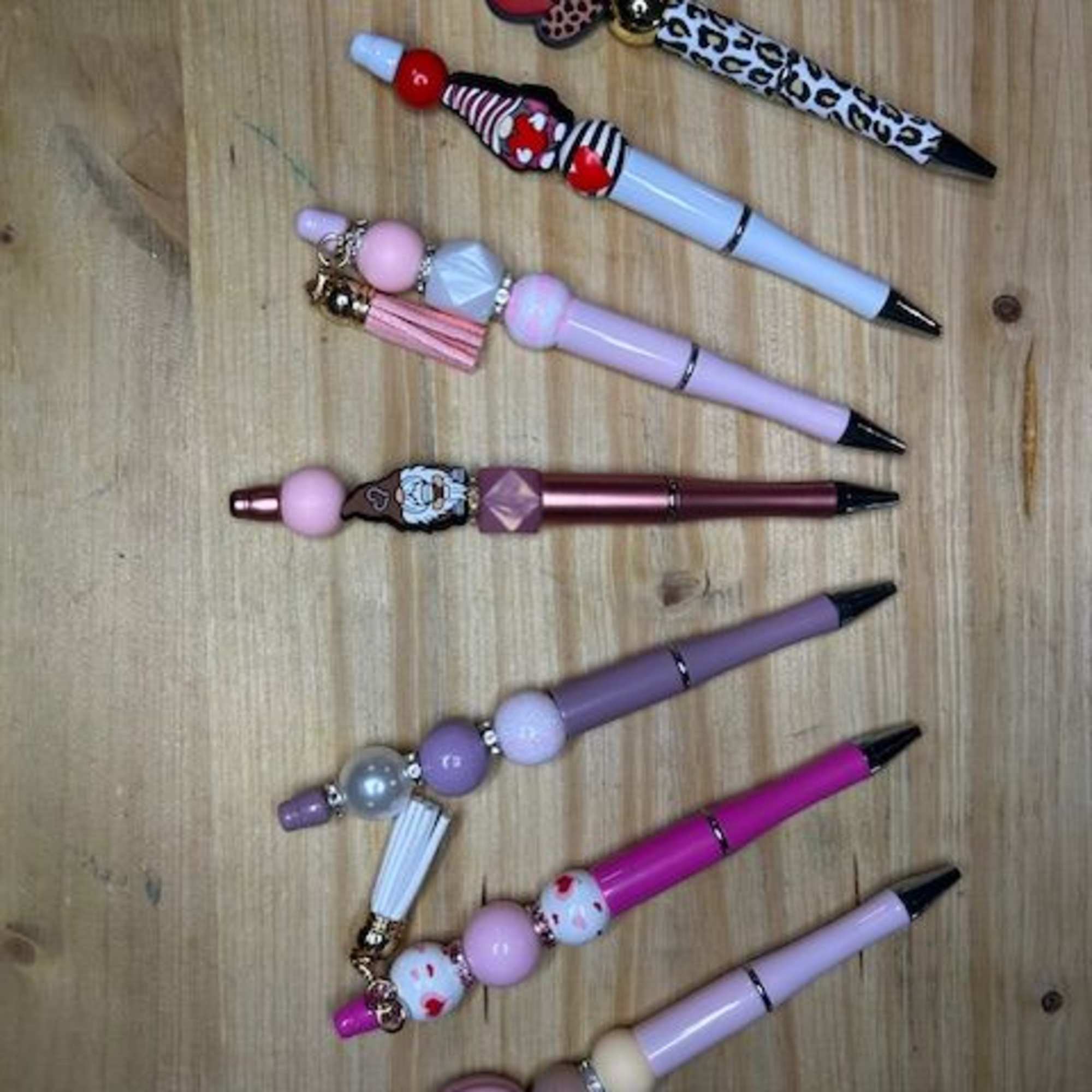 Decorative beaded pens arranged on a wooden surface, photo 2 of 3