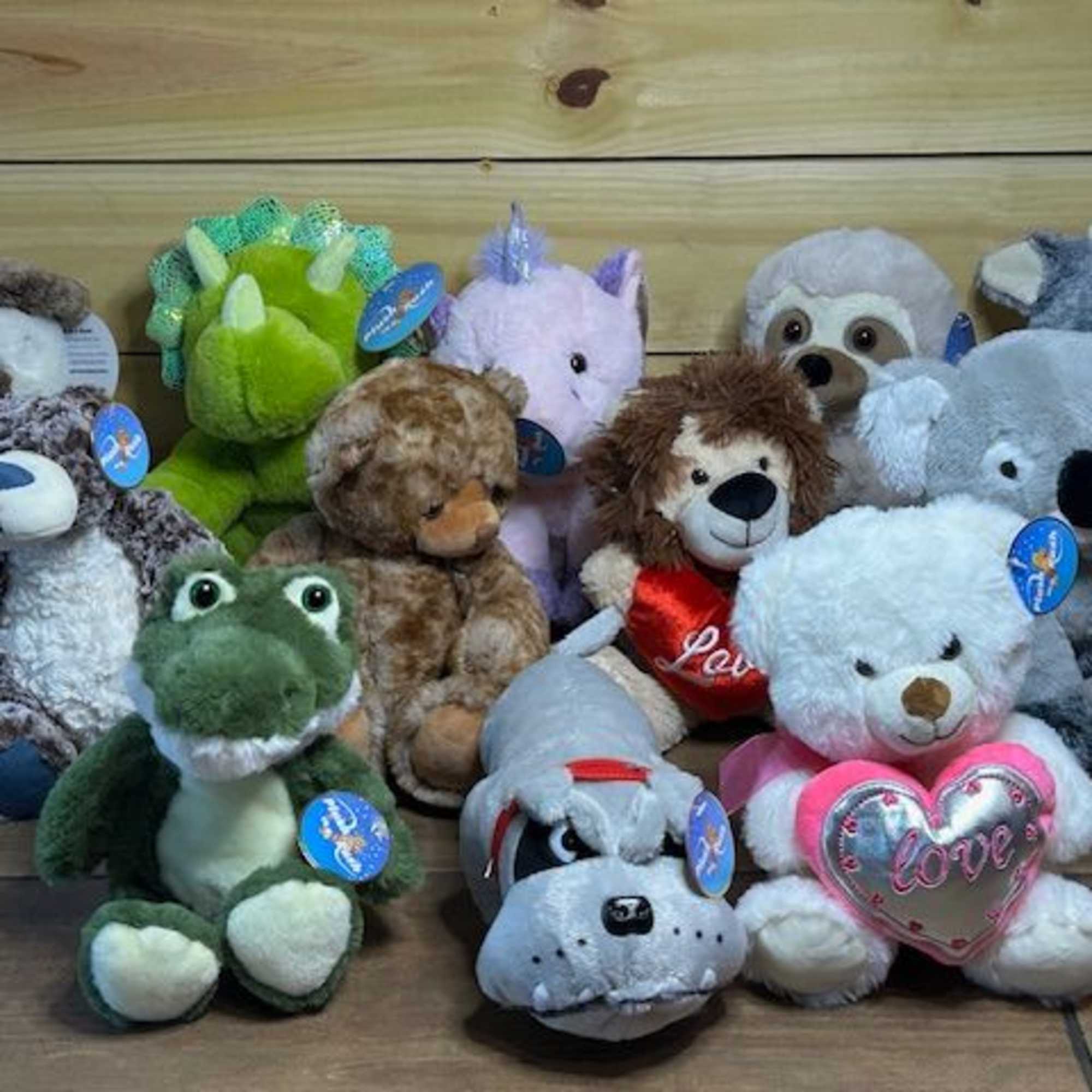 Assorted plush stuffed animals arranged on a wooden floor