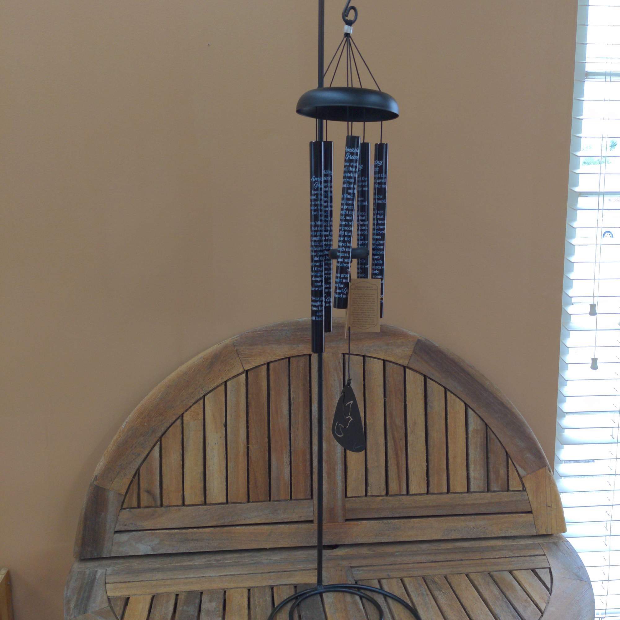 Black metal wind chime hanging above a wooden bench
