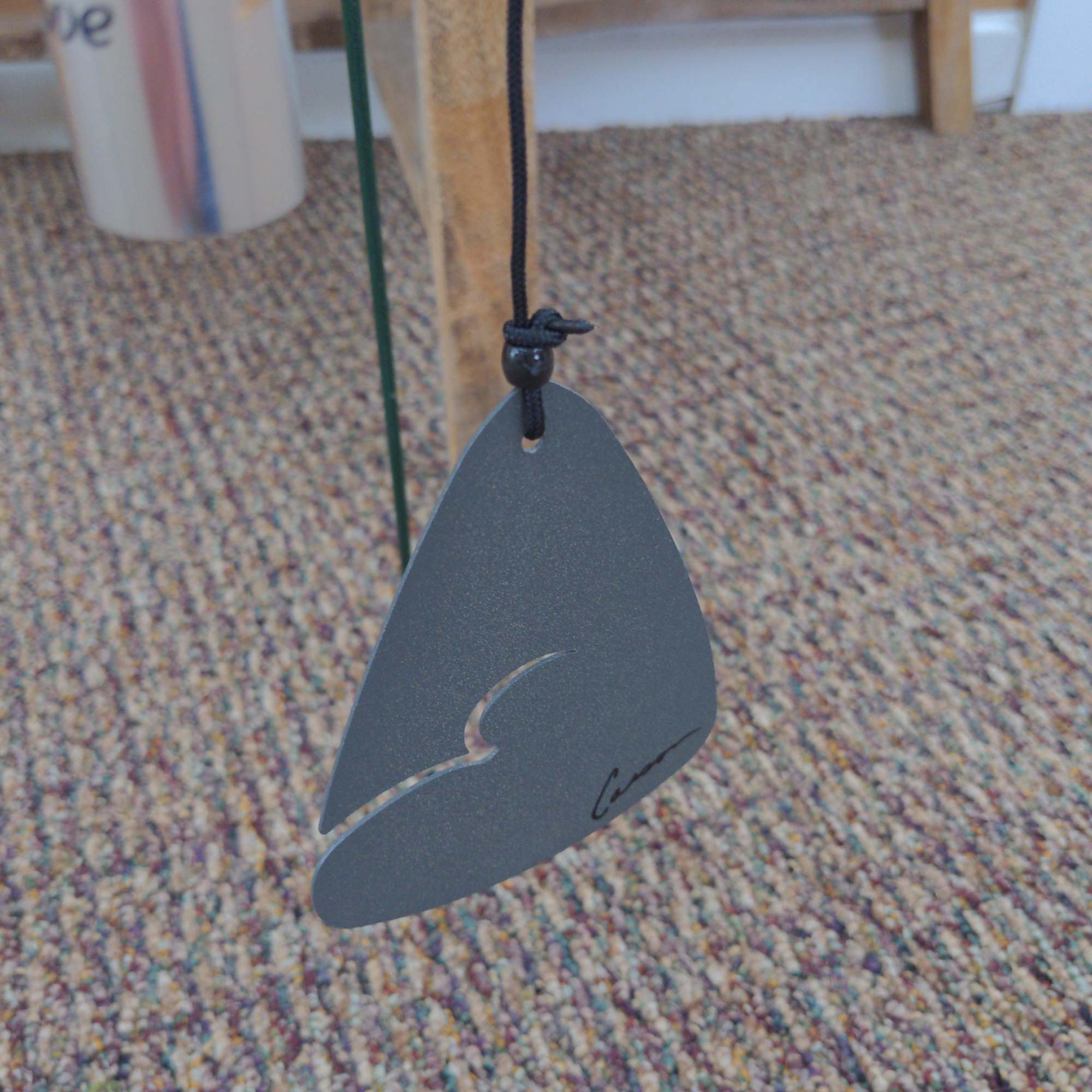 Gray hanging ornament with a black cord and cutout design