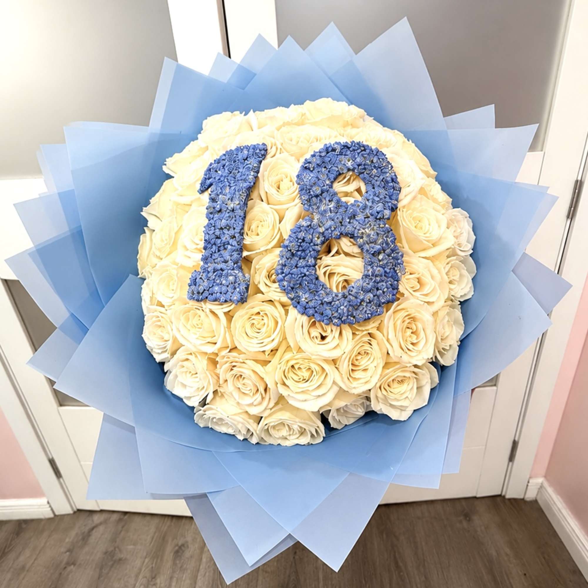 Cream rose bouquet with blue "18" topper and blue wrapping