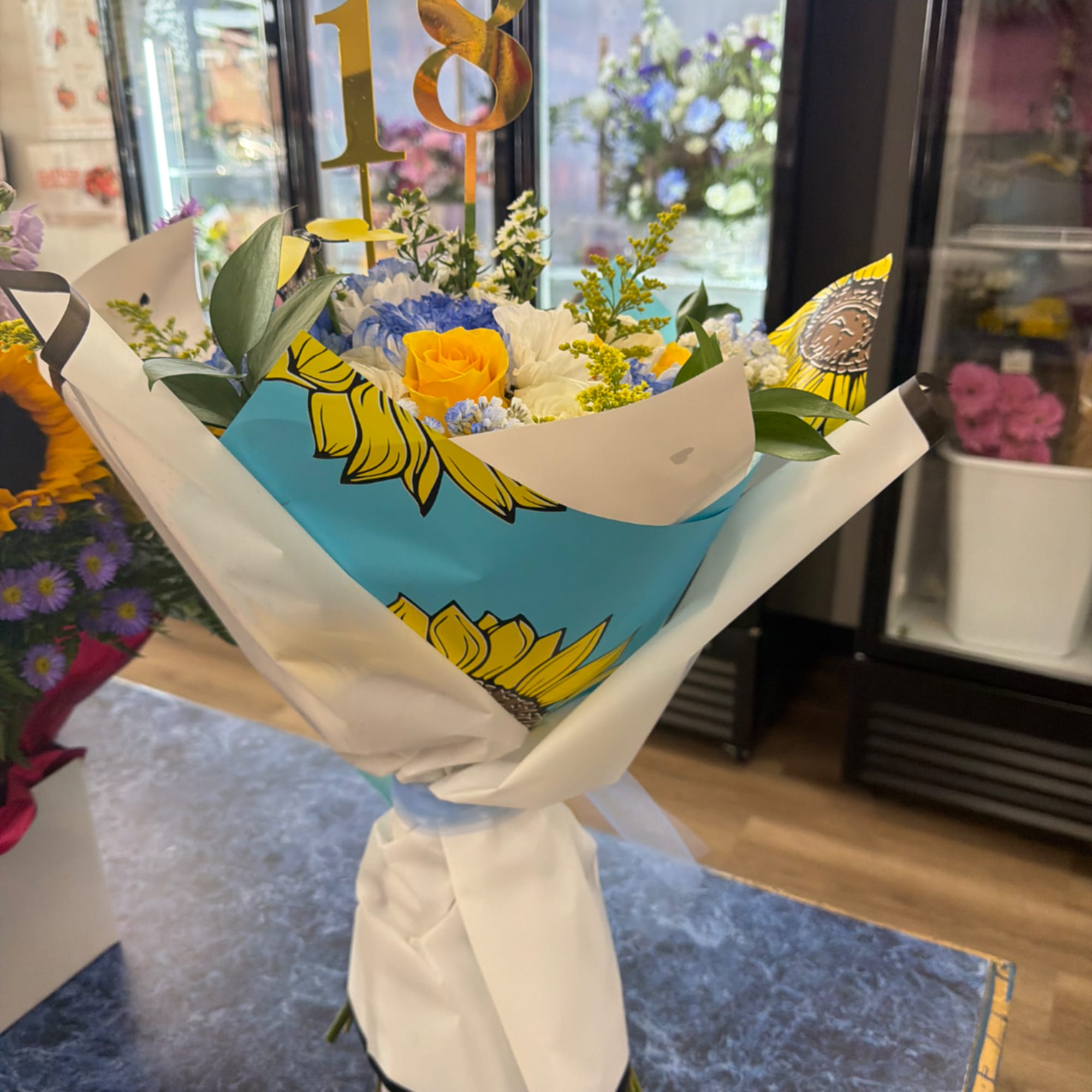Bouquet of yellow and blue flowers wrapped in white paper