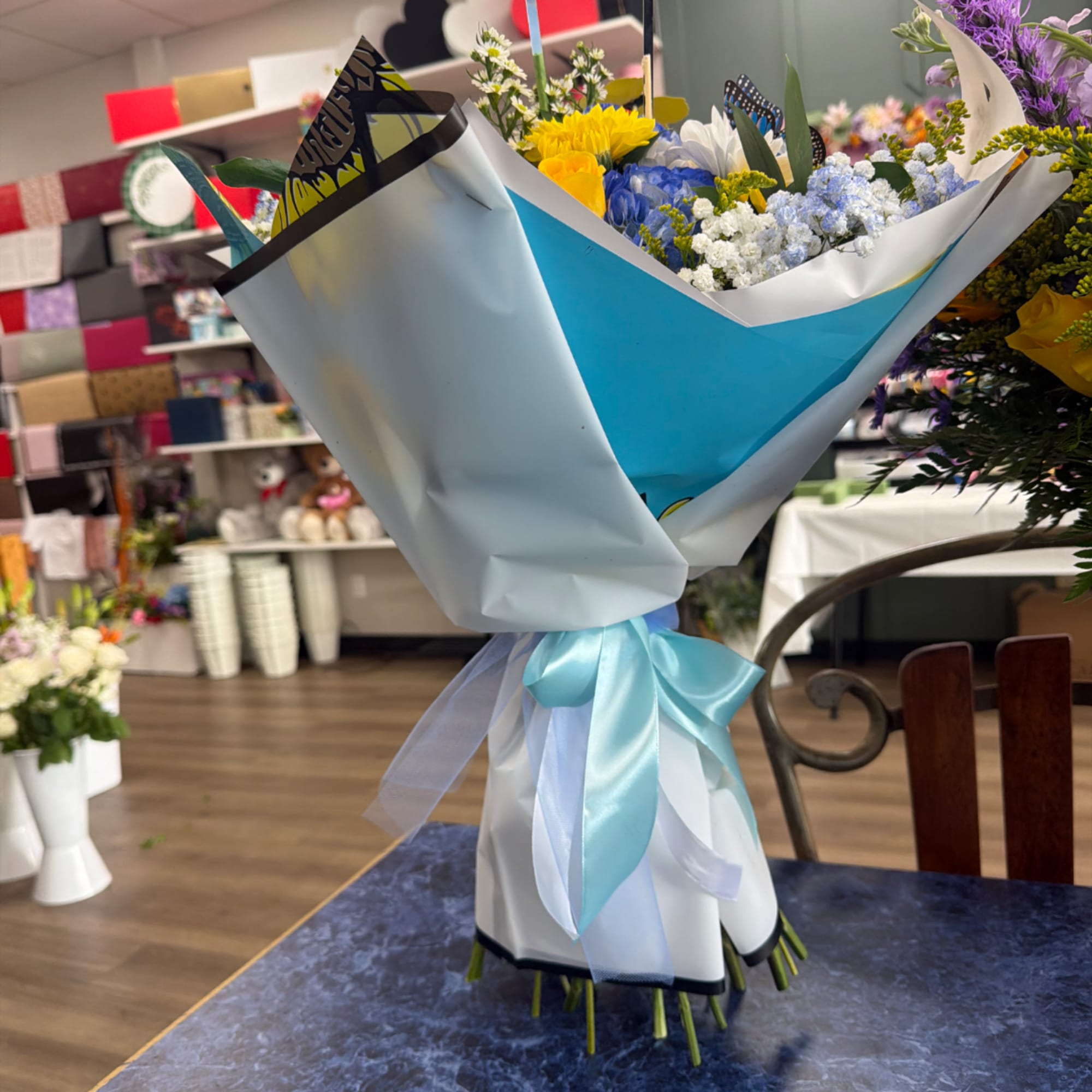 Wrapped bouquet of mixed flowers with a blue ribbon