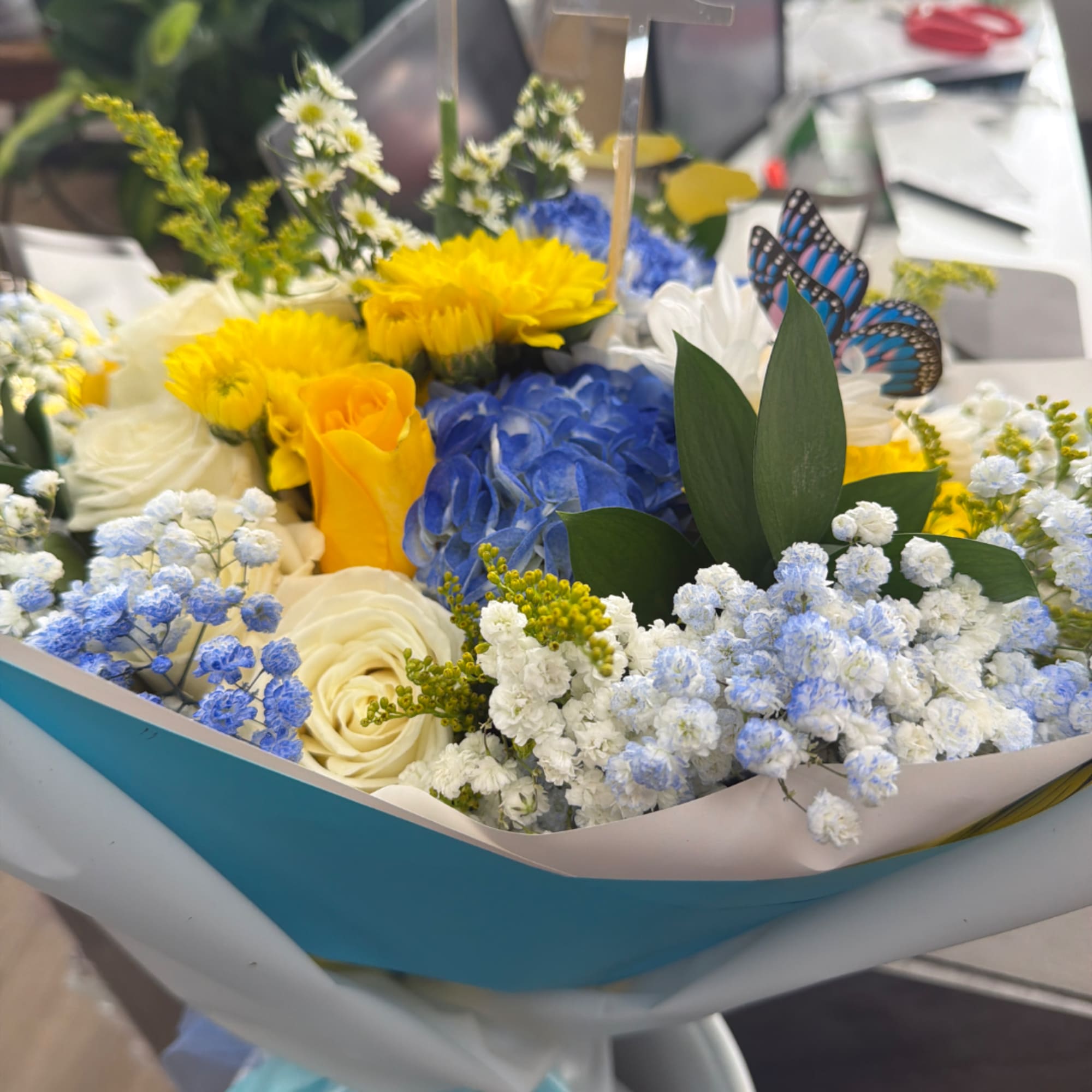 Mixed bouquet with yellow, blue, and white flowers in wrapping paper