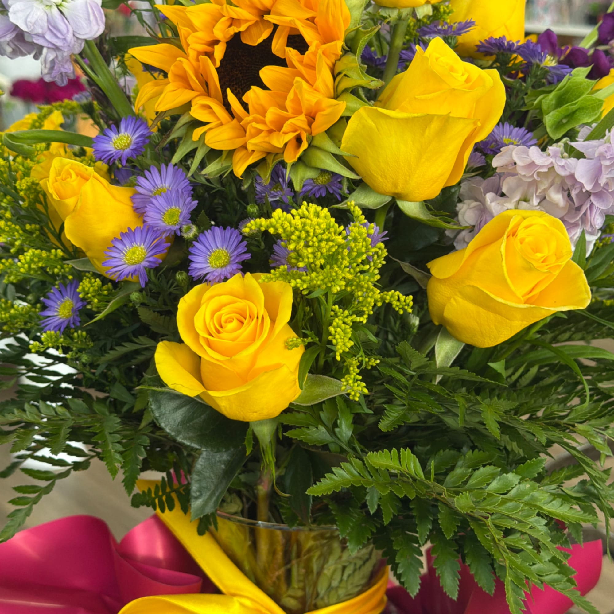 Bouquet of yellow roses and purple daisies in a glass vase