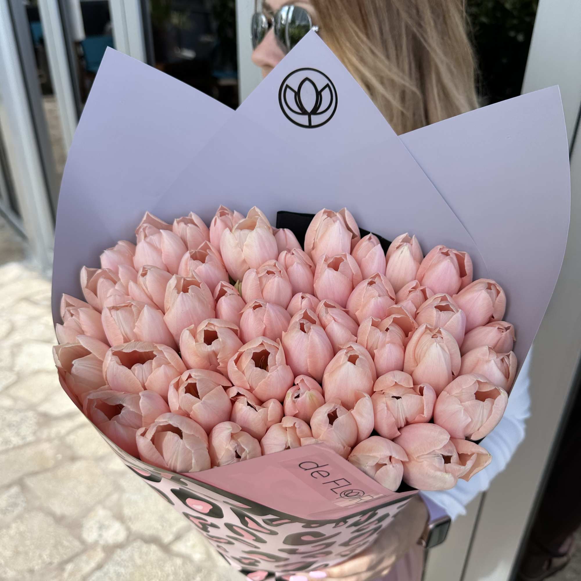 Large bouquet of pale pink tulips wrapped in lavender and pink paper