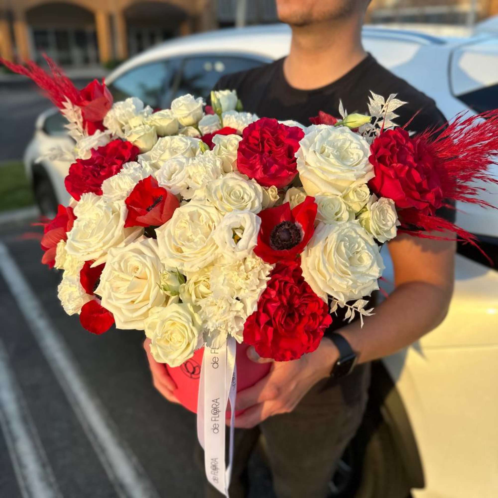 Large bouquet of red and white roses with red feather accents