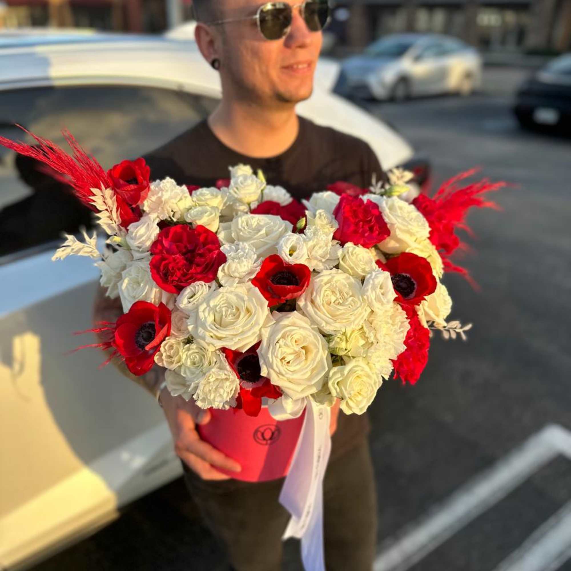Large bouquet of red and white roses in a pink hat box
