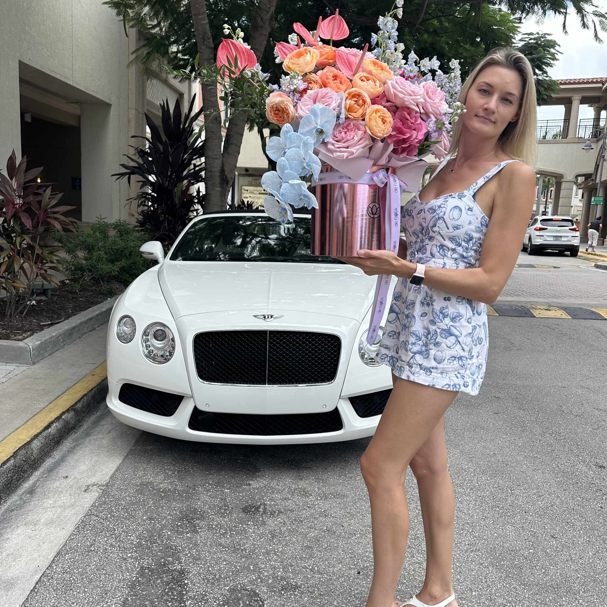 Woman holding a large pastel flower arrangement in a metallic box