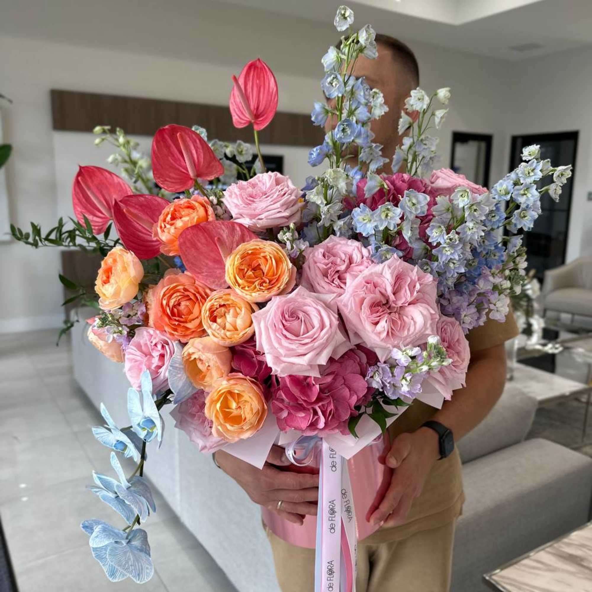 Large bouquet of pink, peach, and blue flowers in a pink wrap