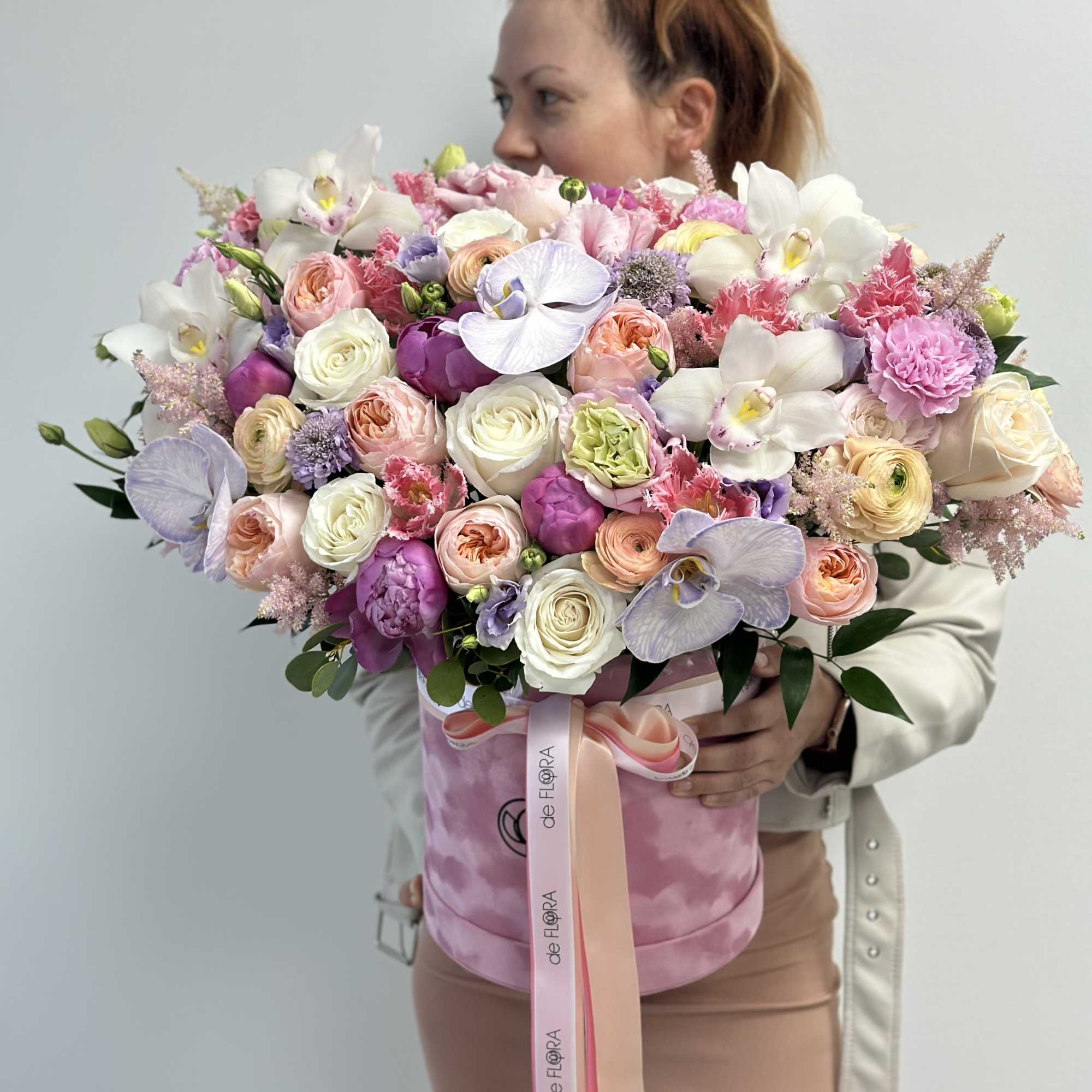 Large pastel bouquet of roses, orchids, and carnations in a pink hat box