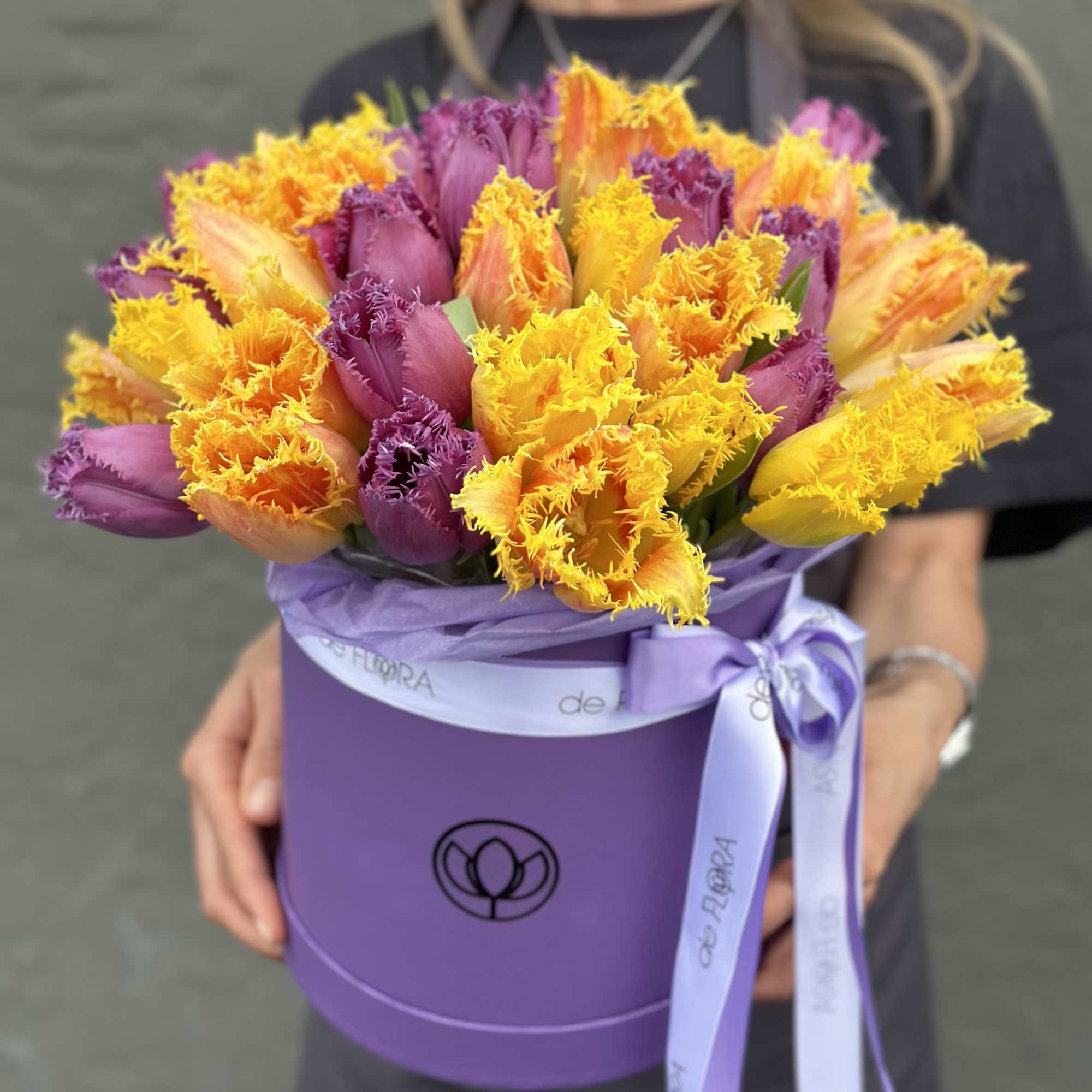 Bouquet of fringed tulips in purple, orange, and yellow in a lavender hatbox