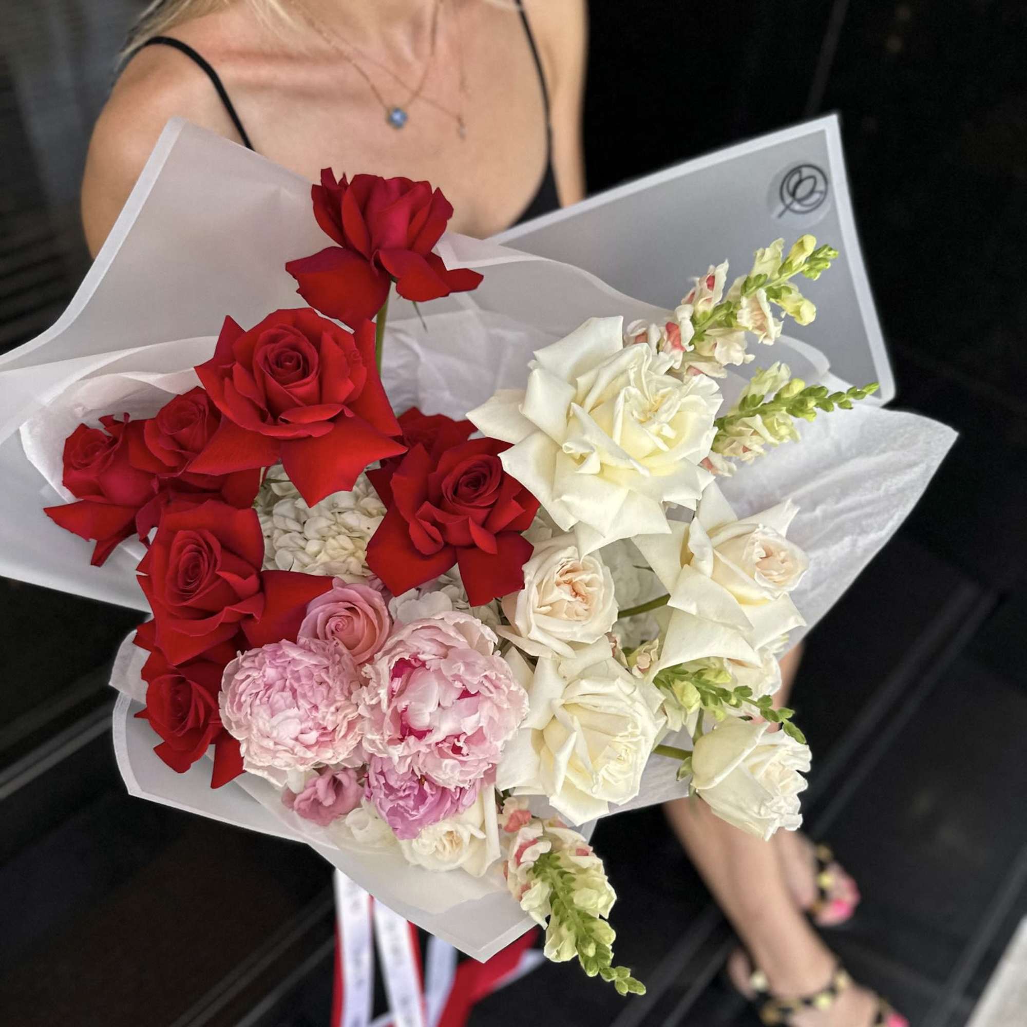 Bouquet of red, white, and pink roses wrapped in white paper