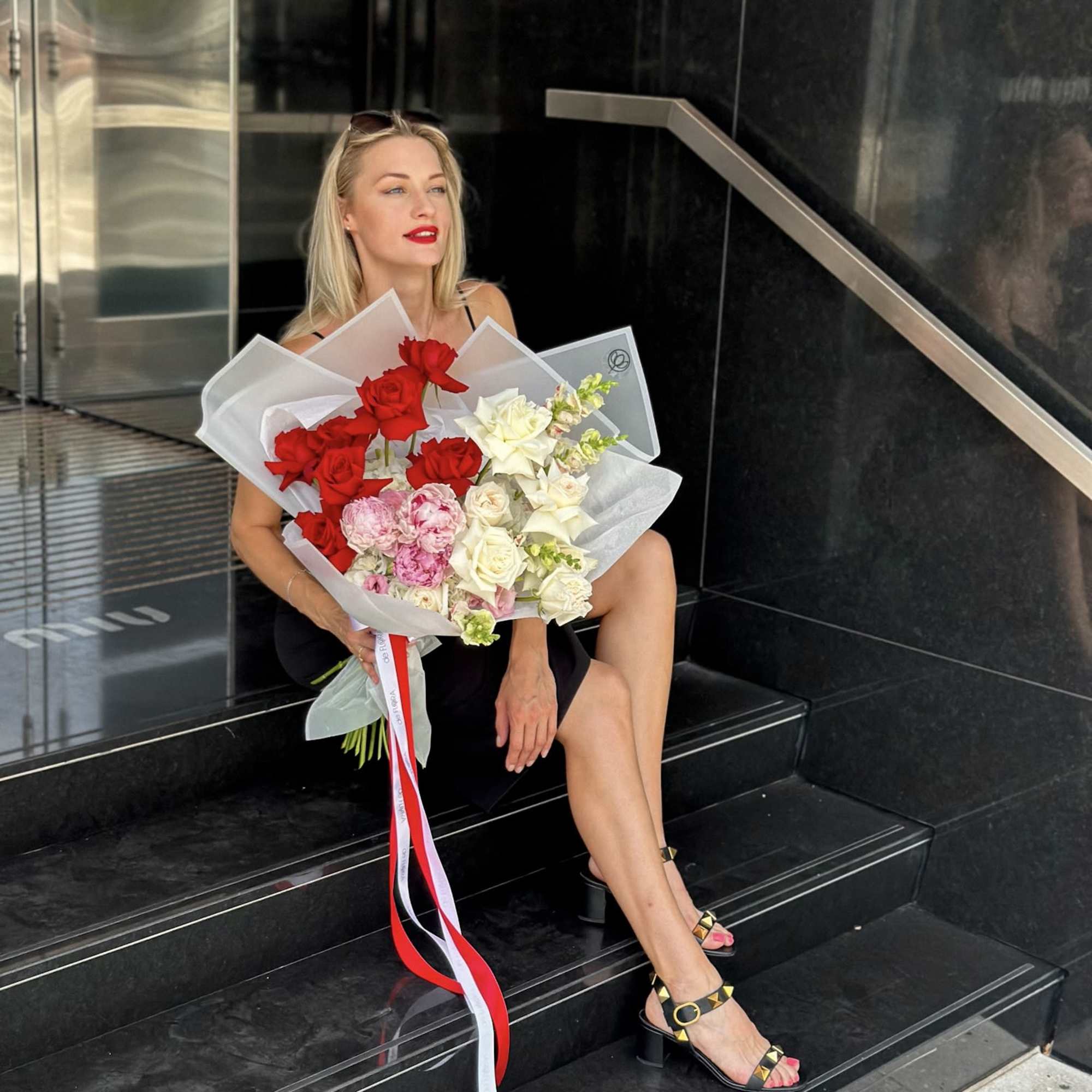 Woman holding a large bouquet of red, white, and pink roses