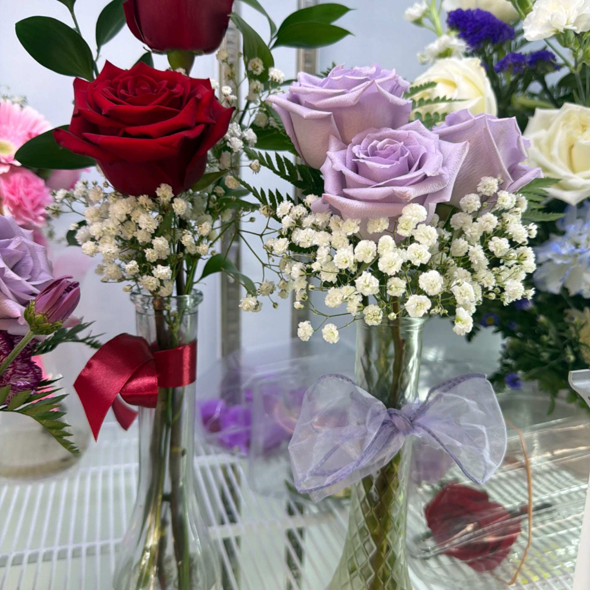 Rose arrangements in glass vases with baby's breath and ribbon bows