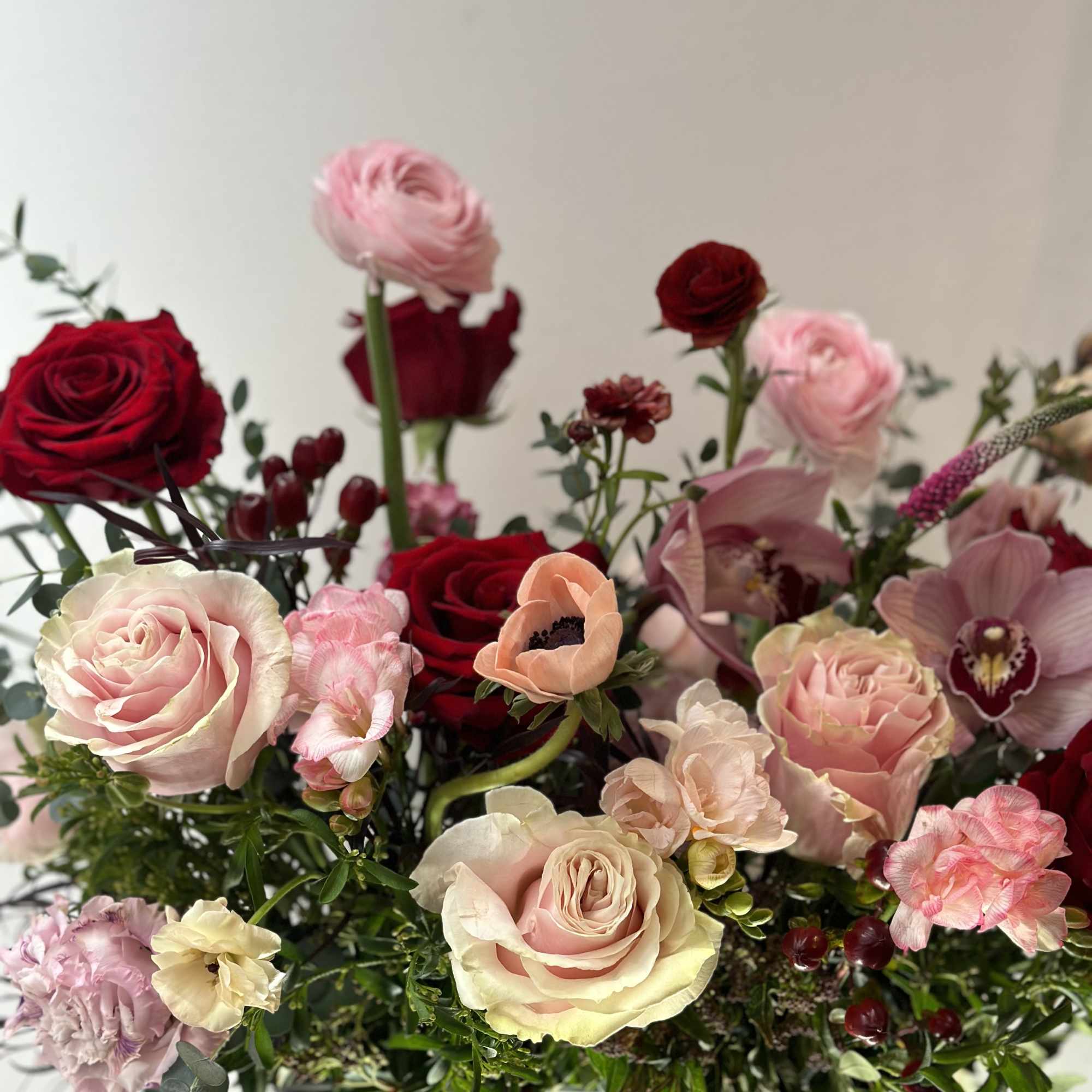Mixed bouquet of roses and pink blooms in a green vase