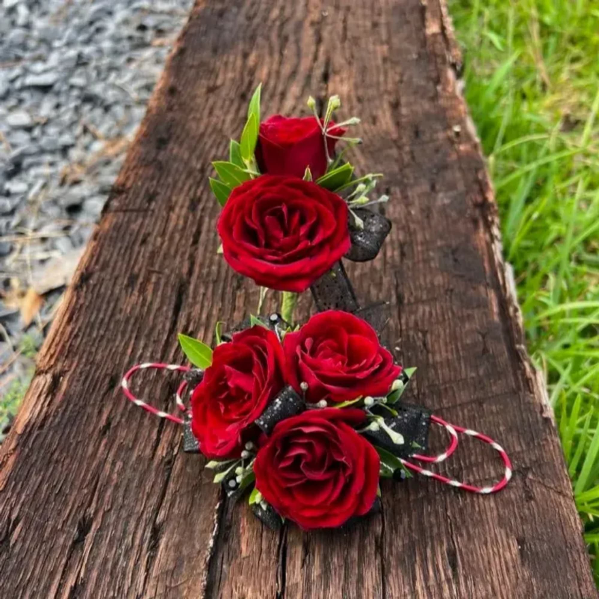 Red rose corsage and boutonniere set on a wooden surface